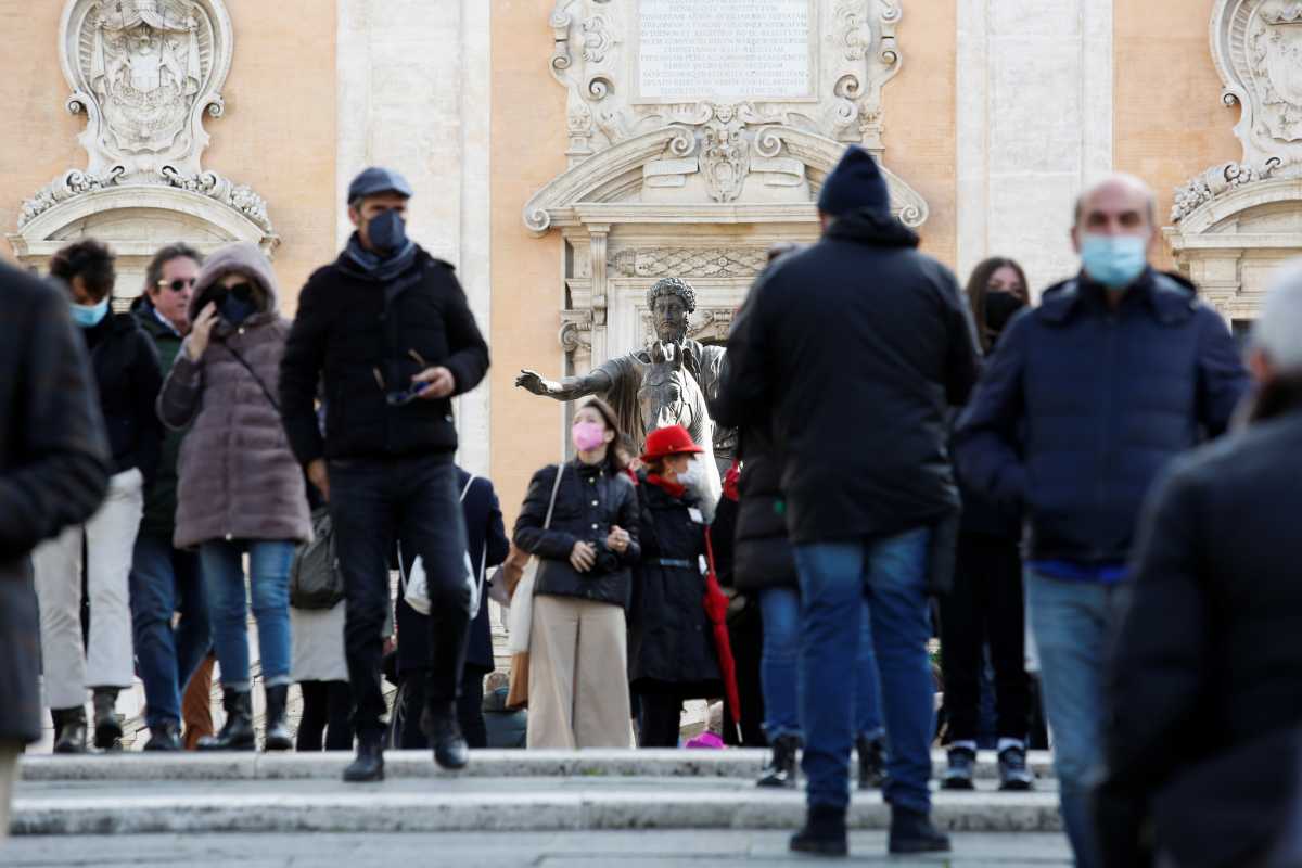 People wearing protective face masks walk past a statue at Capitoline Square (Piazza del Campidoglio) on Capitoline Hill, on the day before coronavirus disease (COVID-19) health passes, known as Green Passes, become mandatory on public transport, in Rome, Italy December 5, 2021. REUTERS
