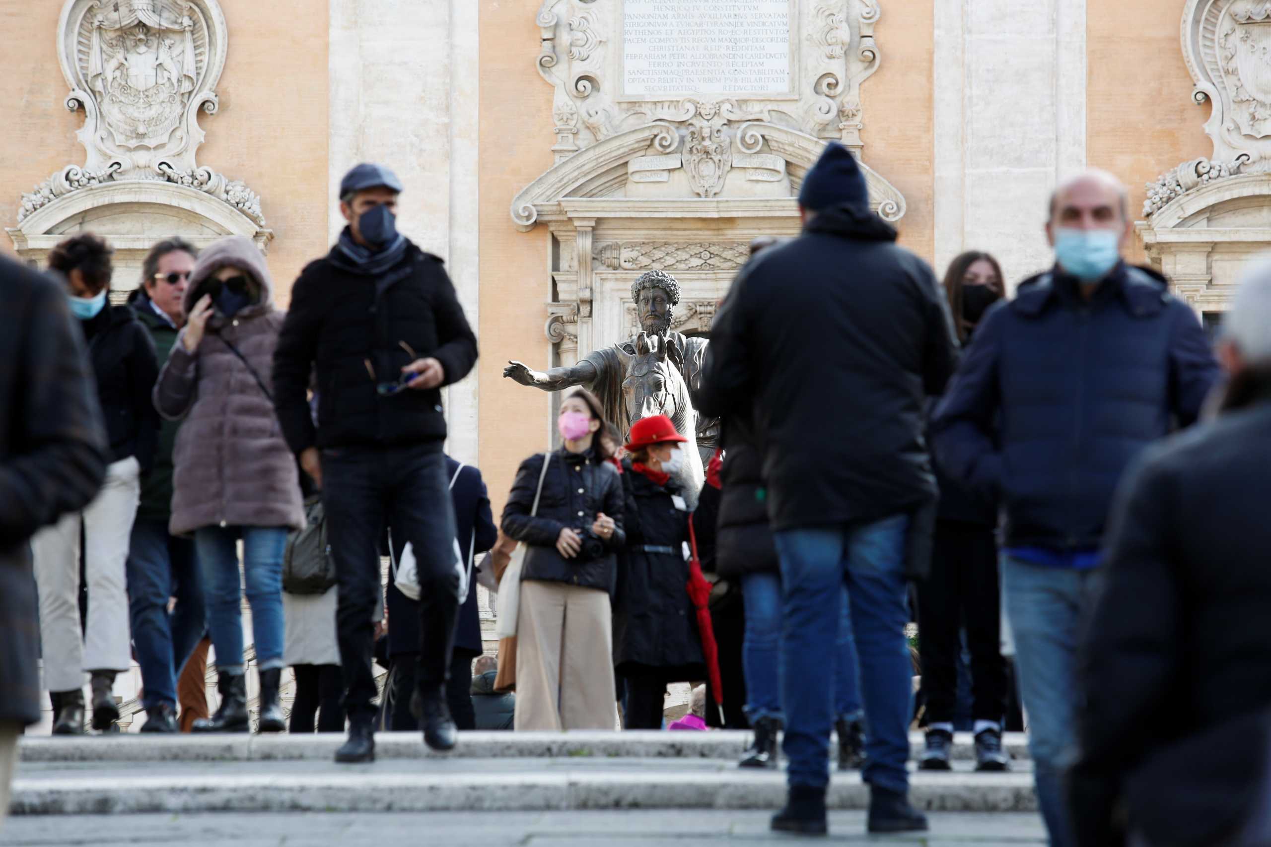 People wearing protective face masks walk past a statue at Capitoline Square (Piazza del Campidoglio) on Capitoline Hill, on the day before coronavirus disease (COVID-19) health passes, known as Green Passes, become mandatory on public transport, in Rome, Italy December 5, 2021. REUTERS