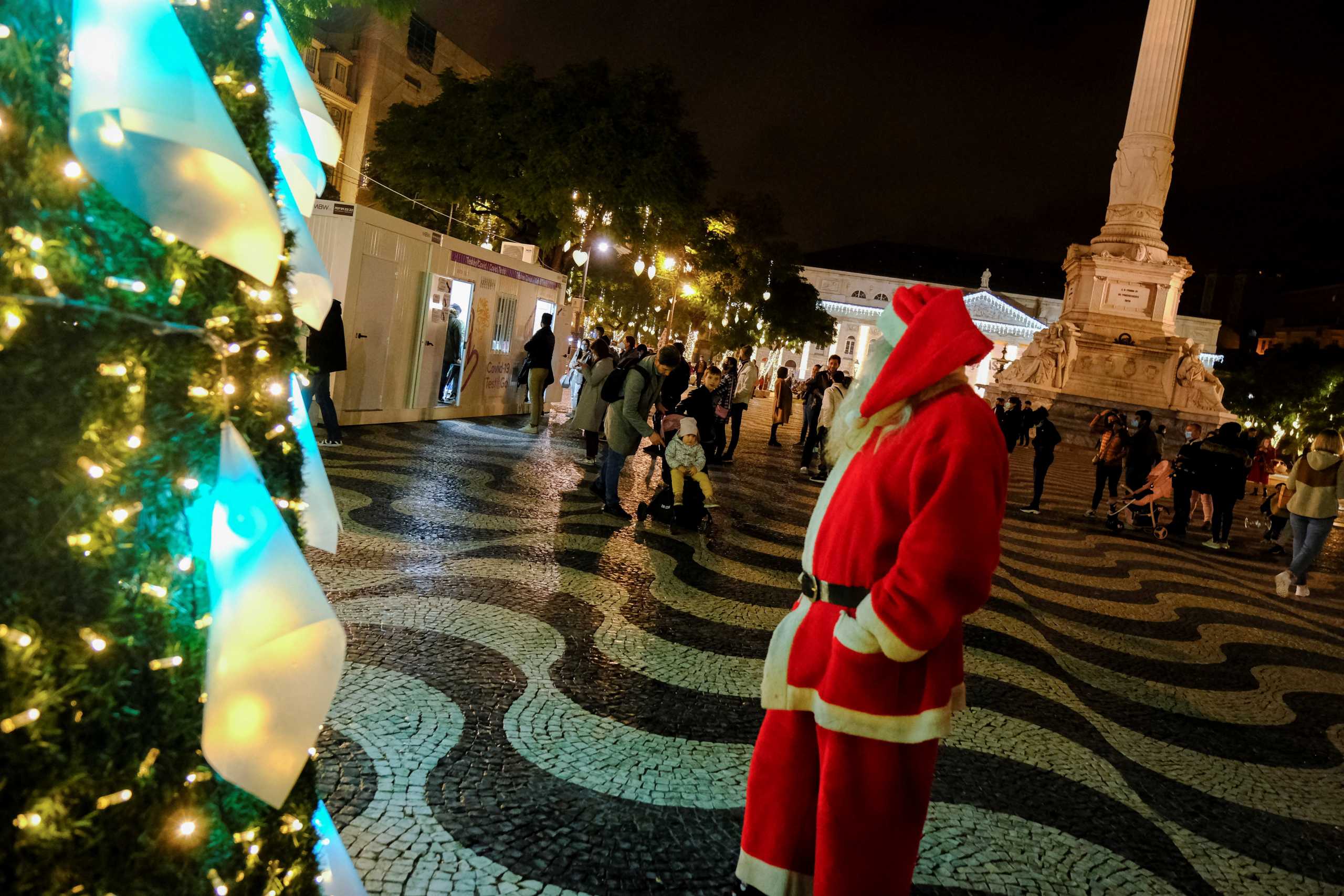 A man dressed as Santa watches as people wait in line on the day before Christmas eve to do tests for the coronavirus disease (COVID-19) in Rossio square, Lisbon, Portugal, December 23, 2021. Picture taken December 23, 2021. REUTERS