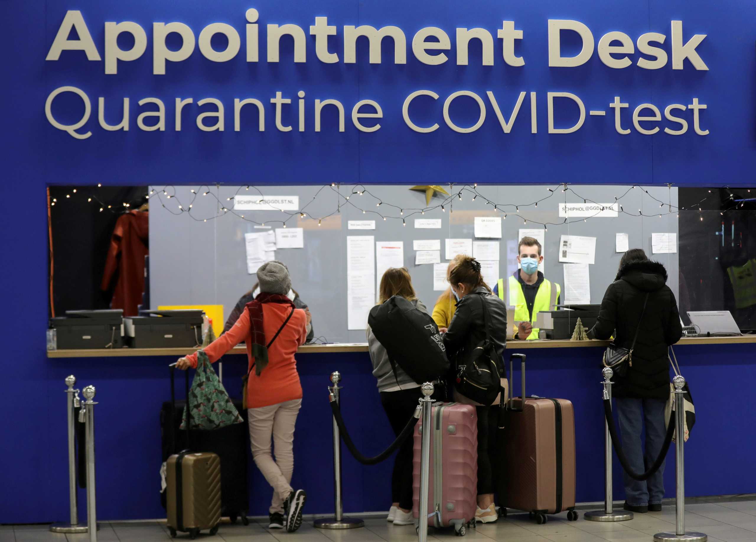 FILE PHOTO: People wait in front of an "Appointment Desk" for quarantine and coronavirus disease (COVID-19) test appointments inside Schiphol Airport, after Dutch health authorities said that 61 people who arrived in Amsterdam on flights from South Africa tested positive for COVID-19, in Amsterdam, Netherlands, November 27, 2021. REUTERS