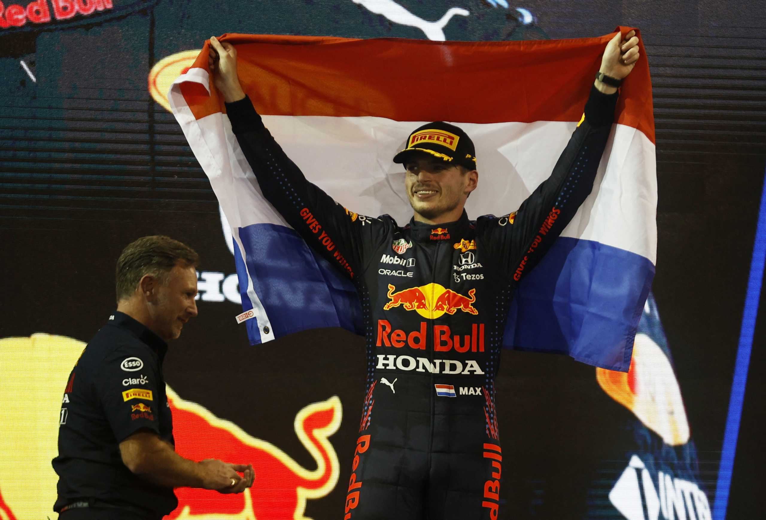 Formula One F1 - Abu Dhabi Grand Prix - Yas Marina Circuit, Abu Dhabi, United Arab Emirates - December 12, 2021 Red Bull's Max Verstappen celebrates winning the race and the world championship with the Netherlands flag and team principal Christian Horner on the podium REUTERS
