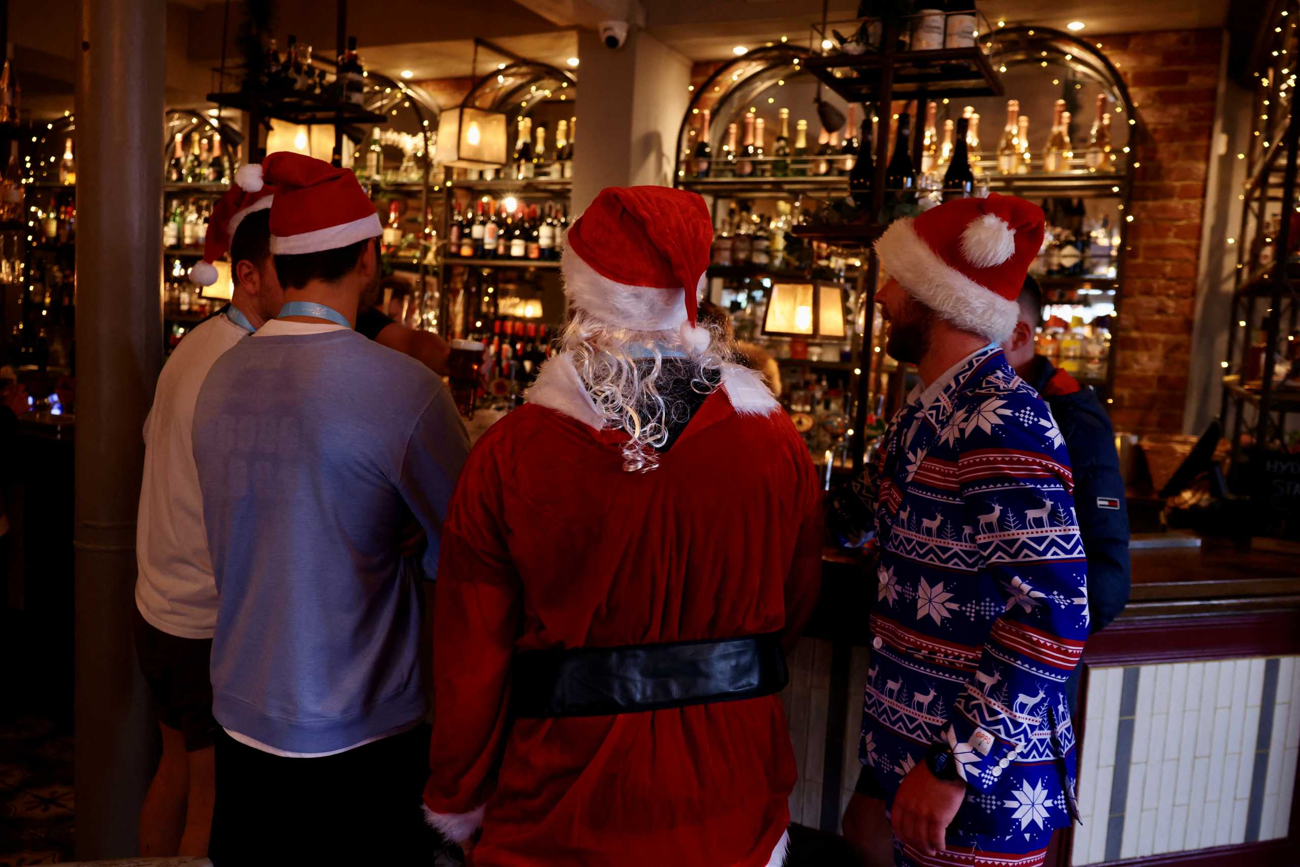 People dressed in Christmas outfits stand at a bar amid the coronavirus disease (COVID-19) outbreak, in London, Britain December 19, 2021. REUTERS