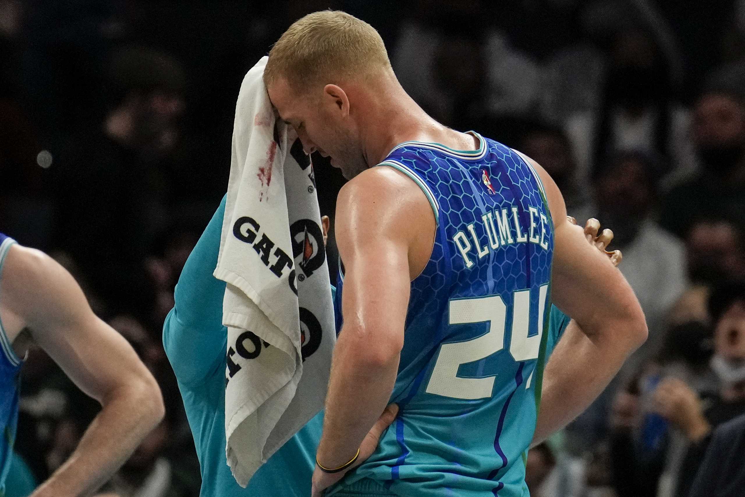 Jan 8, 2022; Charlotte, North Carolina, USA; A trainer wipes blood from the eyebrow of Charlotte Hornets center Mason Plumlee (24) after an elbow from Milwaukee Bucks forward Giannis Antetokounmpo (not pictured) during the second half at the Spectrum Center. Mandatory Credit: Jim Dedmon-USA TODAY Sports