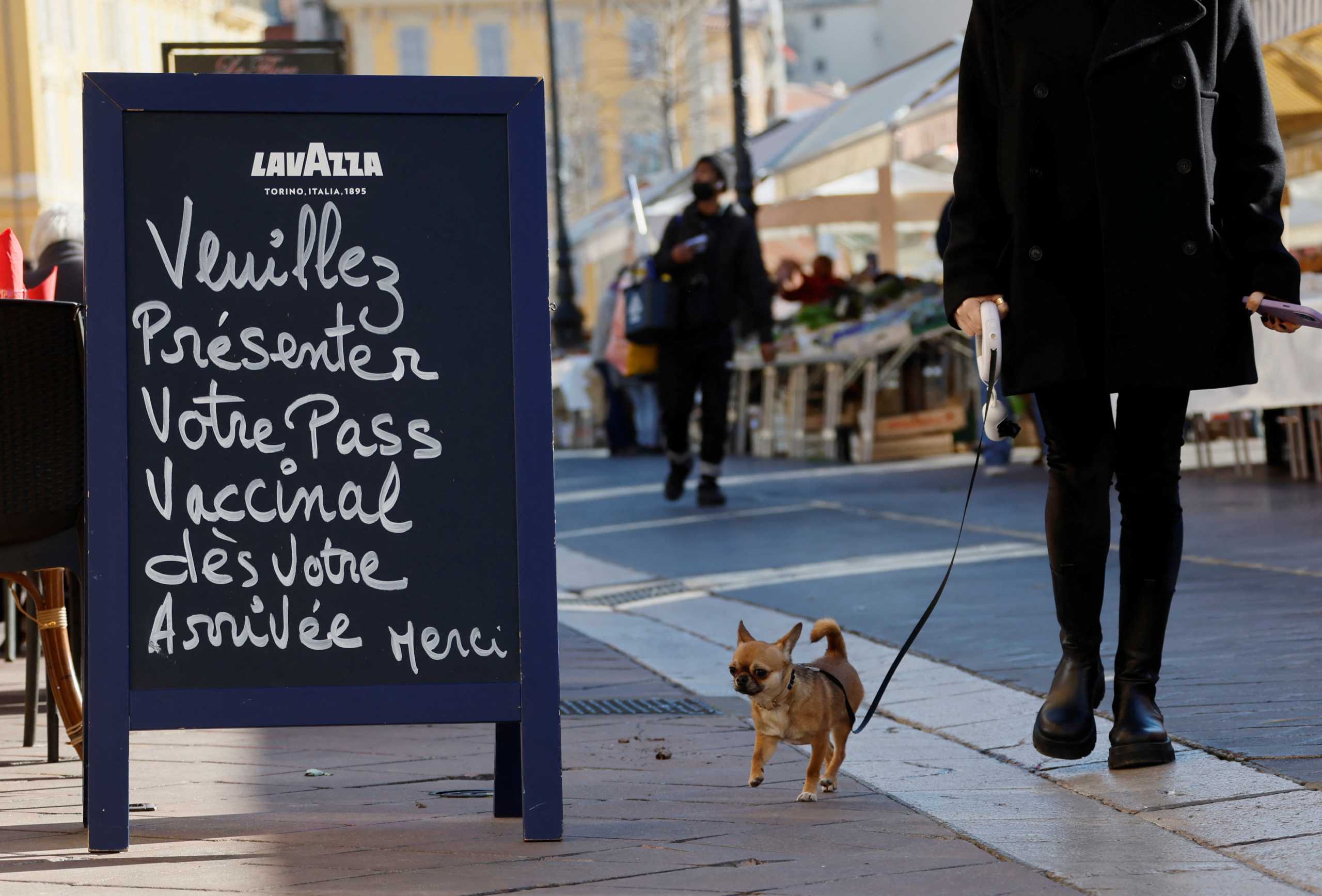 A dog walks past a sign reading "Please, prepare your vaccine pass" at the entrance of a restaurant in Nice, France, January 21, 2022. REUTERS