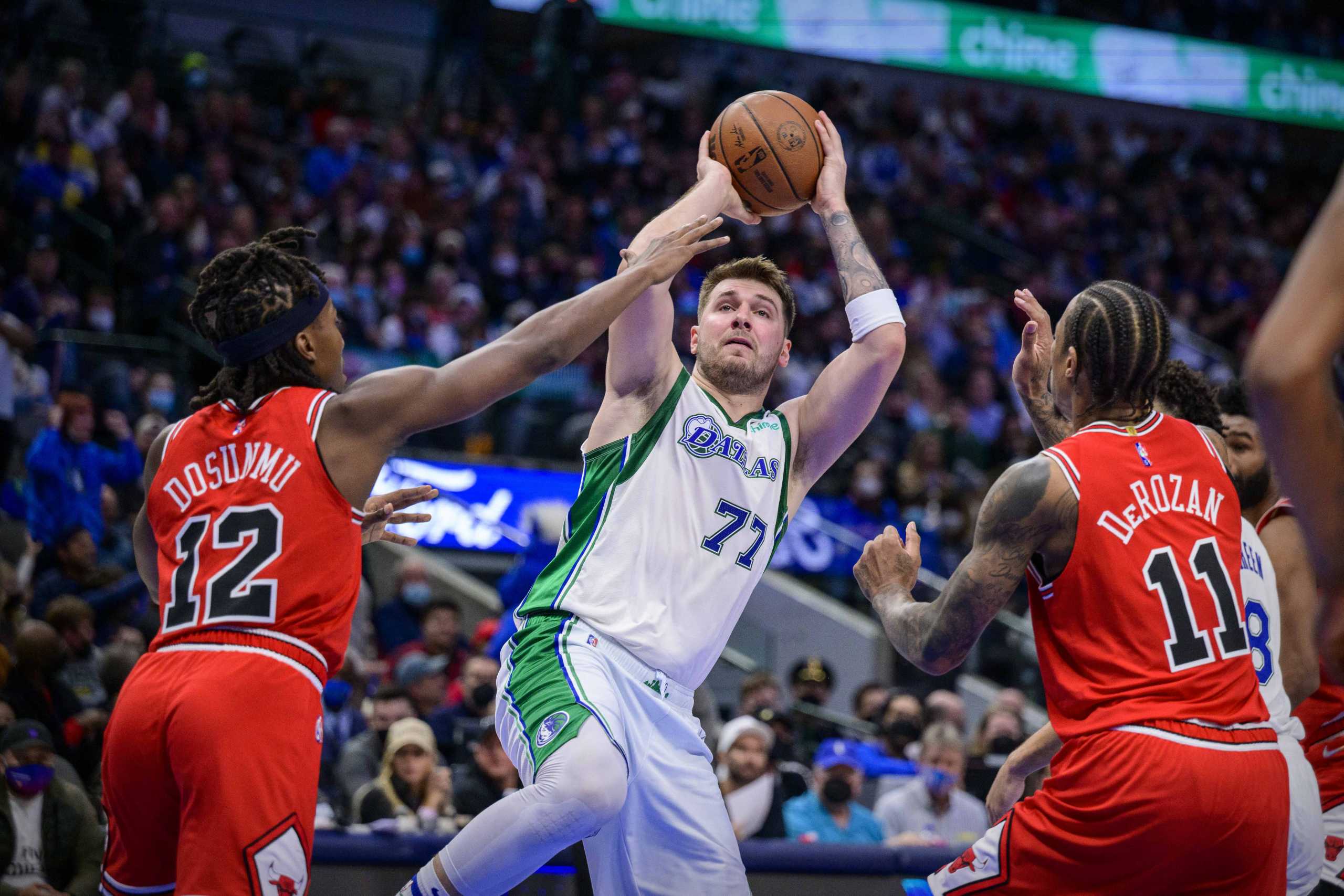 Jan 9, 2022; Dallas, Texas, USA; Dallas Mavericks guard Luka Doncic (77) passes the ball between Chicago Bulls guard Ayo Dosunmu (12) and forward DeMar DeRozan (11) during the second half at the American Airlines Center. Mandatory Credit: Jerome Miron-USA TODAY Sports