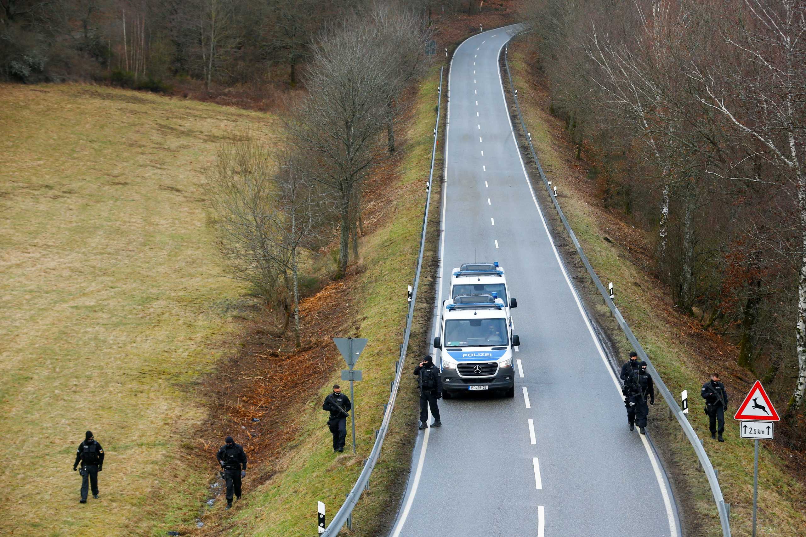 Police officers search the area on a road near the site where two German police officers were fatally shot early January 31, 2022, during a routine traffic stop near Kusel, southwestern Germany, January 31, 2022. REUTERS