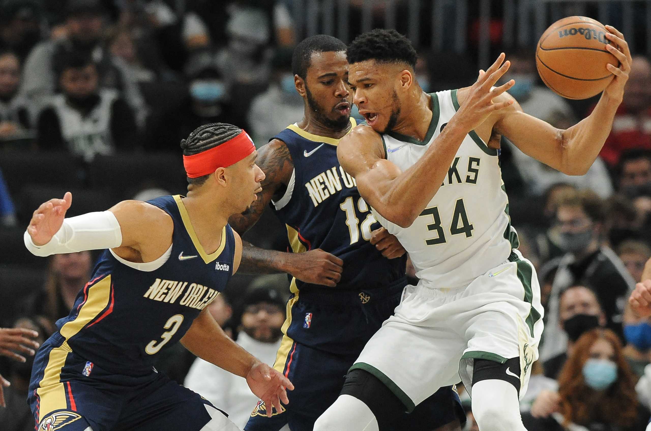 Jan 1, 2022; Milwaukee, Wisconsin, USA;  Milwaukee Bucks forward Giannis Antetokounmpo (34) controls the ball against New Orleans Pelicans guard Josh Hart (3)  and forward Gary Clark (12) in the first half at Fiserv Forum. Mandatory Credit: Michael McLoone-USA TODAY Sports