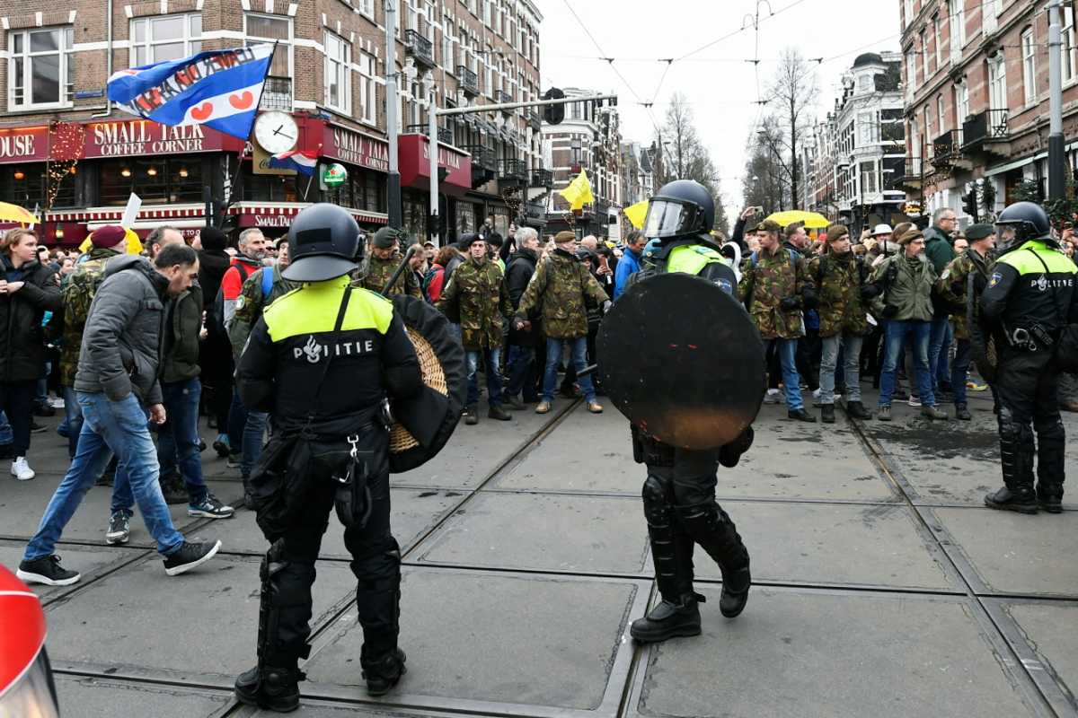 Police officers stand guard as opponents of restrictions imposed in the Netherlands to contain the spread of the coronavirus disease (COVID-19) protest despite a ban by local authorities, in Amsterdam, Netherlands, January 2, 2022. REUTERS