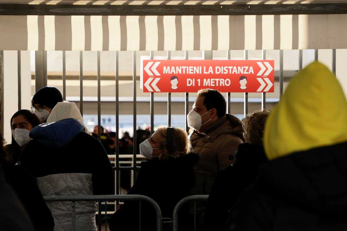 A sign that reads "Keep a distance of 1 meter" is seen as people queue to receive coronavirus disease (COVID-19) vaccines at Mostra d'Oltremare vaccination centre in Naples, Italy, January, 8 2022. REUTERS