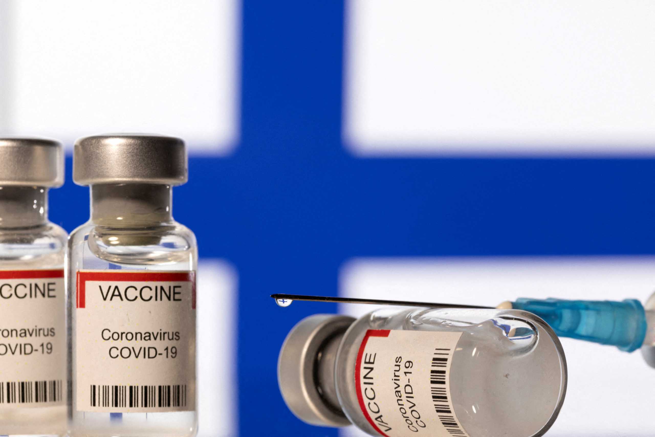 FILE PHOTO: Vials labelled "VACCINE Coronavirus COVID-19" and a syringe are seen in front of a displayed flag of Finland in this illustration taken December 11, 2021. REUTERS