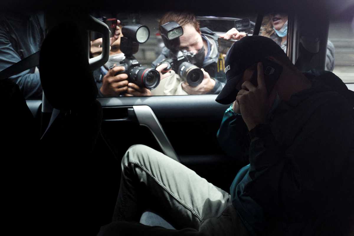 Members of the media photograph an unidentified man departing the car park at the offices of Serbian tennis player Novak Djokovic's legal team under police escort in Melbourne, Australia, January 15, 2022. REUTERS