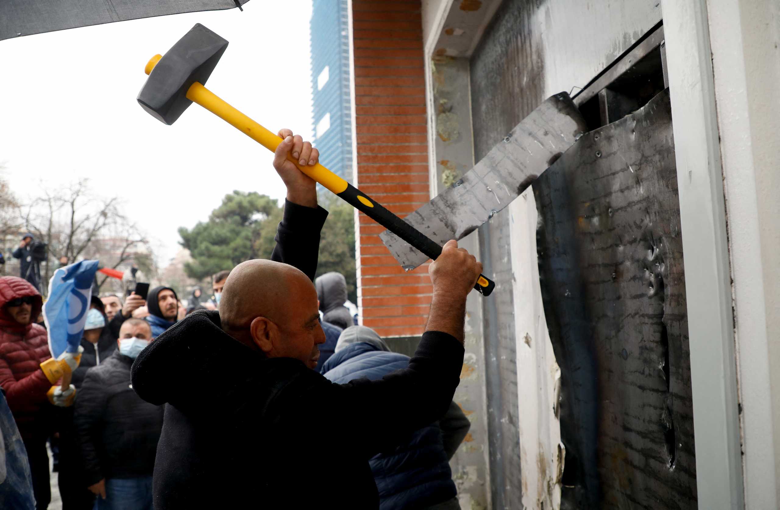A protester attacks the headquarters of the Democratic Party in Tirana, Albania, January 8, 2022. REUTERS