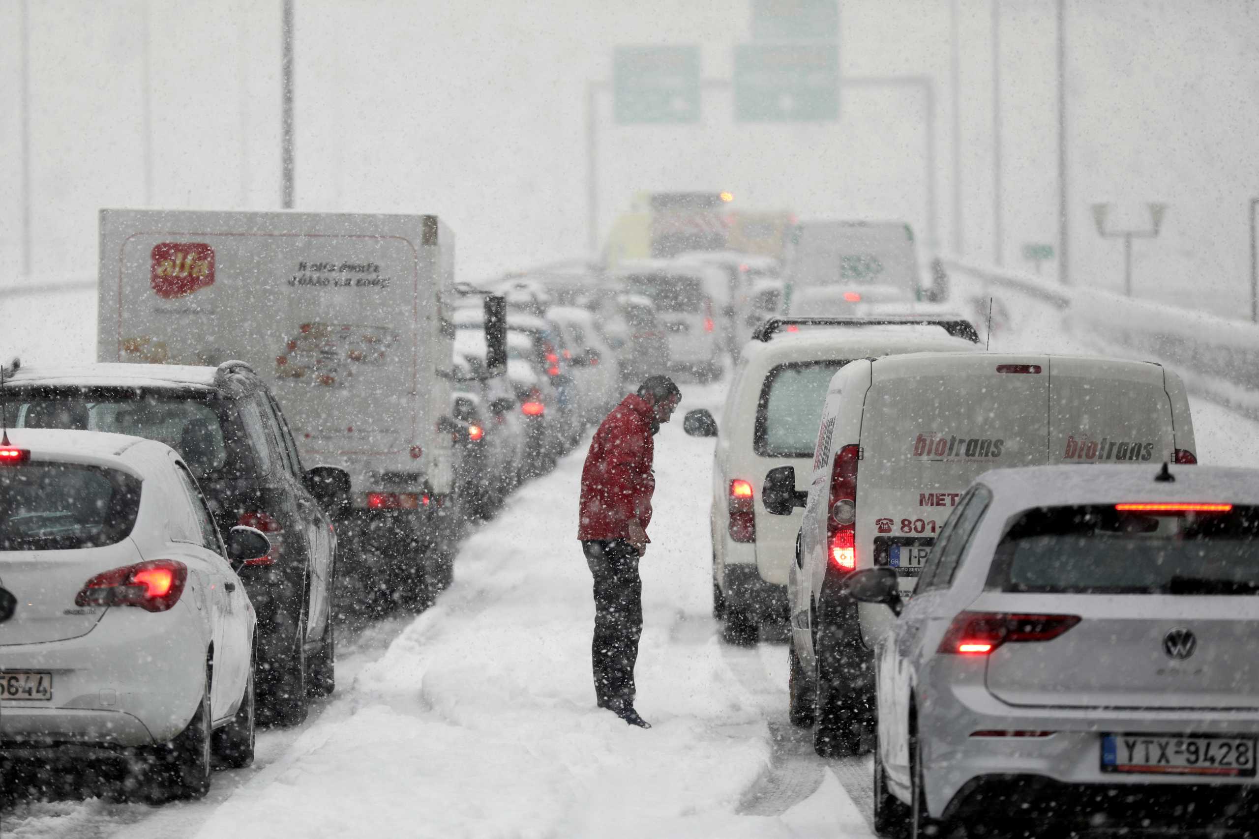 A man stands next to vehicles stuck in traffic in the Attiki Odos motorway, during heavy snowfall in Athens, Greece, January 24, 2022. REUTERS