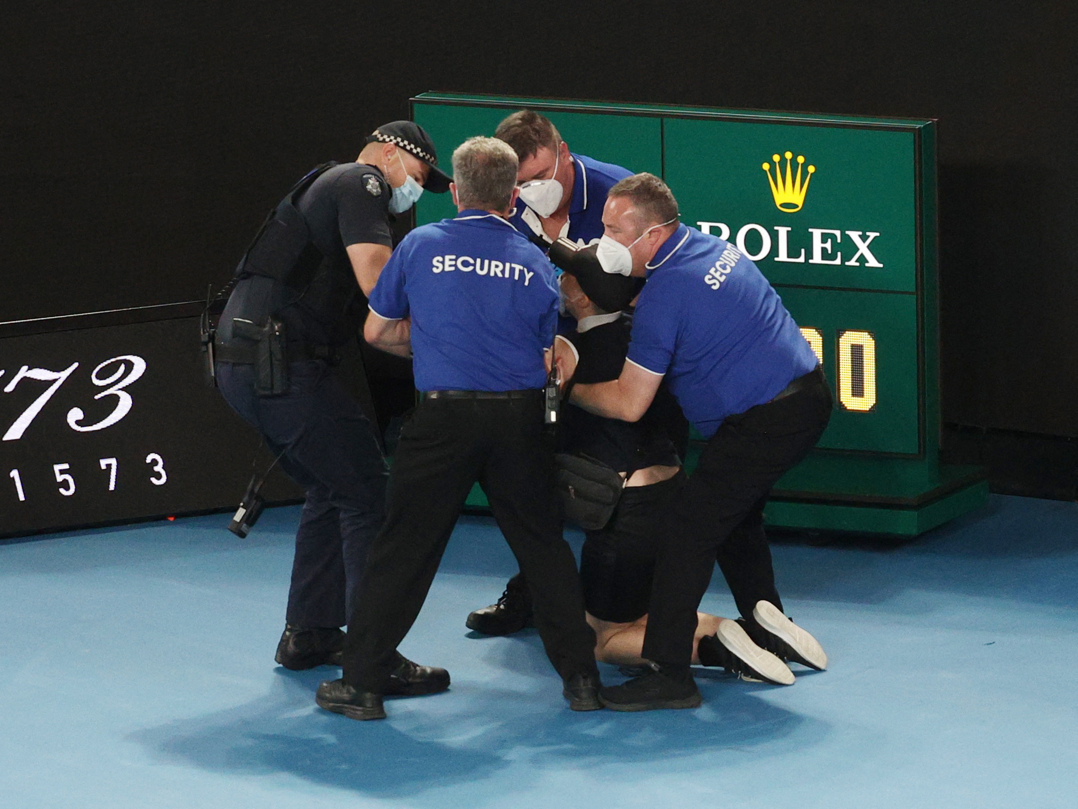 Tennis - Australian Open - Men's Singles Final - Melbourne Park, Melbourne, Australia - January 30, 2022 Man is detained by security and police after he jumps on to the court REUTERS