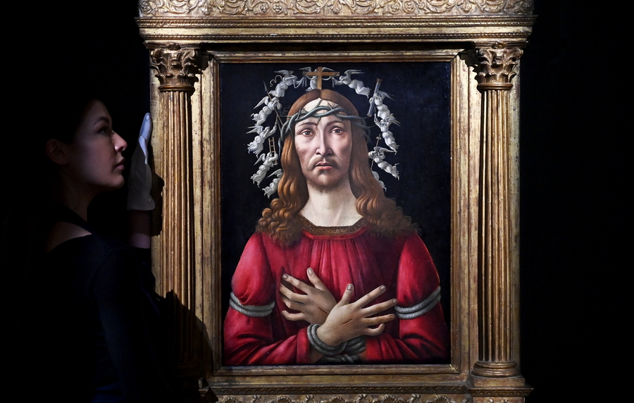 epa09614296 A gallery employee poses for photographers next to a painting titled 'Man Of Sorrows' by Italian Renaissance artist Sandro Botticelli during a photocall at Sotheby's auction house in London, Britain, 01 December 2021. The artwork is estimated to fetch 40 million USD during an Old Masters sale at Sotheby's New York on 27 January 2022.  EPA