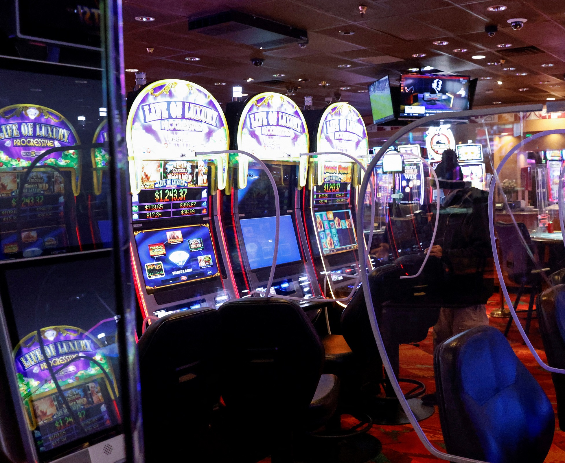 People sit wearing protective face masks, amid the coronavirus disease (COVID-19) pandemic, behind plastic barriers playing slot machines at the Ute Mountain Hotel and Casino in Towaoc, Colorado, U.S., December 15, 2021.  REUTERS