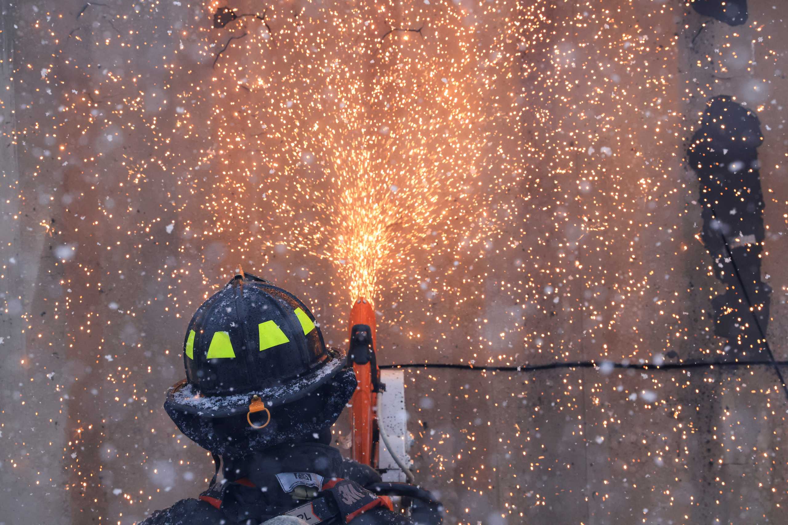 A firefighter cuts holes into a burning shipping container to spray water inside from different angles, a day after evacuation orders, in Louisville, Colorado, U.S., December 31, 2021. REUTERS