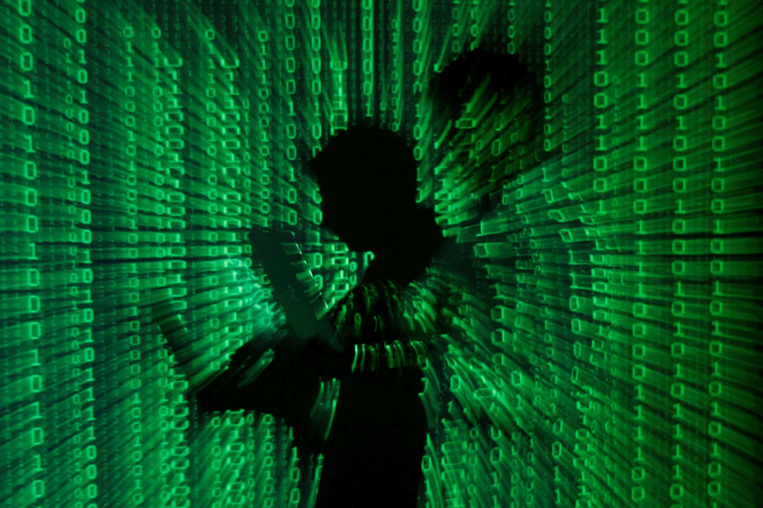 FILE PHOTO: An illustration picture shows a projection of binary code on a man holding a laptop computer, in an office in Warsaw June 24, 2013. REUTERS