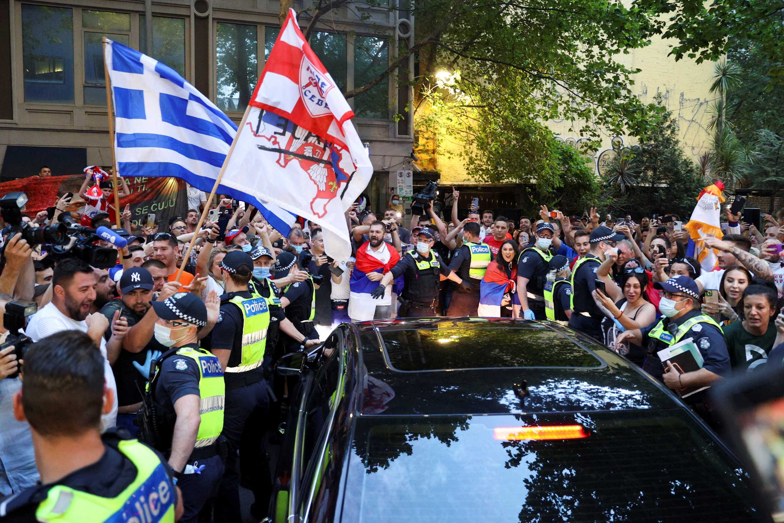 Supporters of Serbian tennis player Novak Djokovic gather around a car outside what is believed to be the location of his lawyer's office during an ongoing day of legal proceedings over the cancellation of his visa to play in the Australian Open, in Melbourne, Australia, January 10, 2022. REUTERS