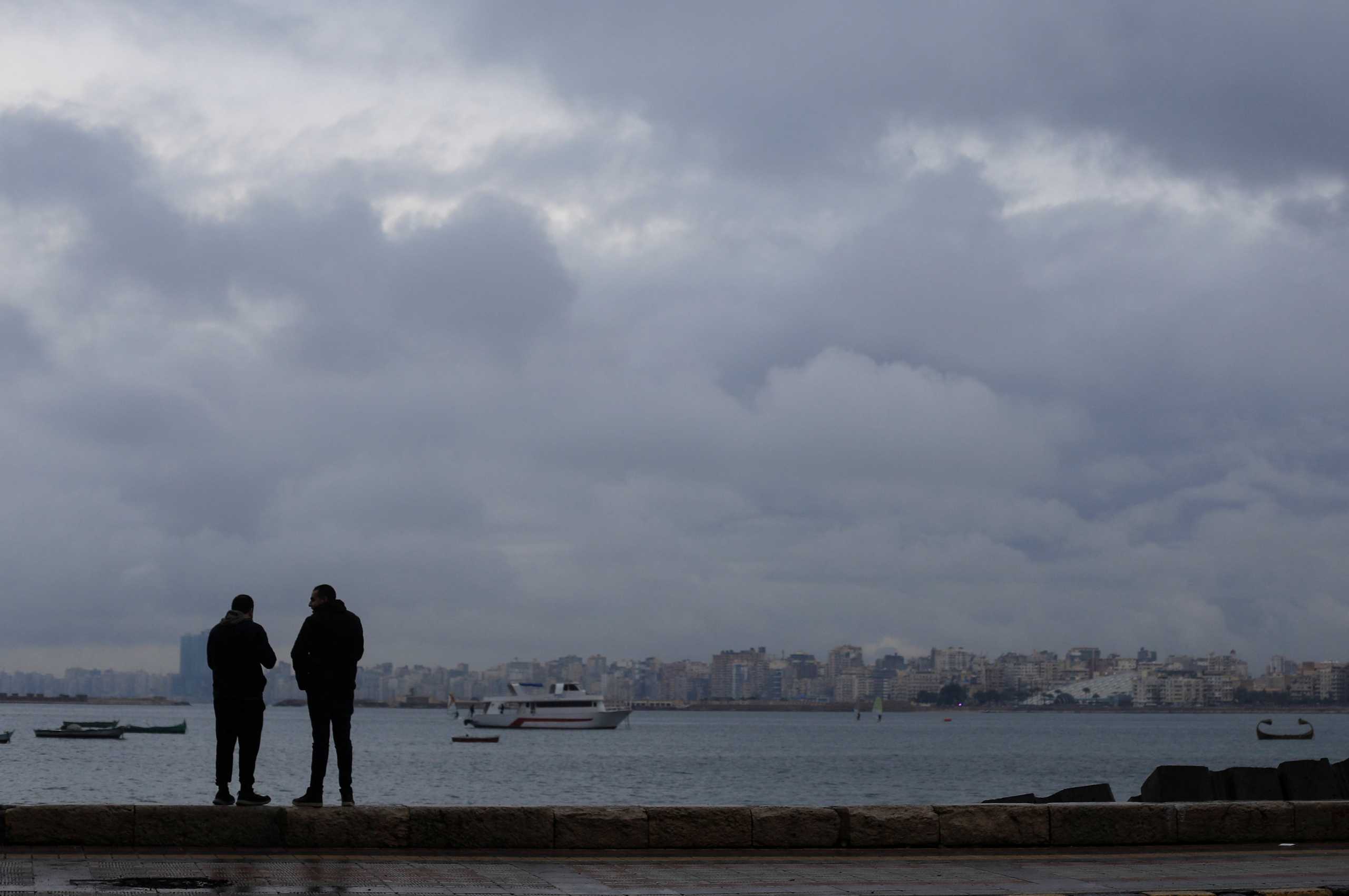 People stand by the sea during rainy weather in the Mediterranean port city of Alexandria, Egypt December 31, 2021. REUTERS