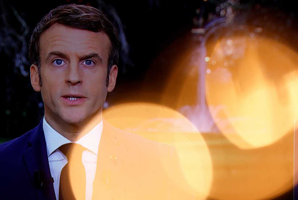 French President Emmanuel Macron is seen on a screen through the light of a Christmas tree as he delivers his New Year's speech to the nation at the Elysee Palace in Paris, France, December 31, 2021. REUTERS