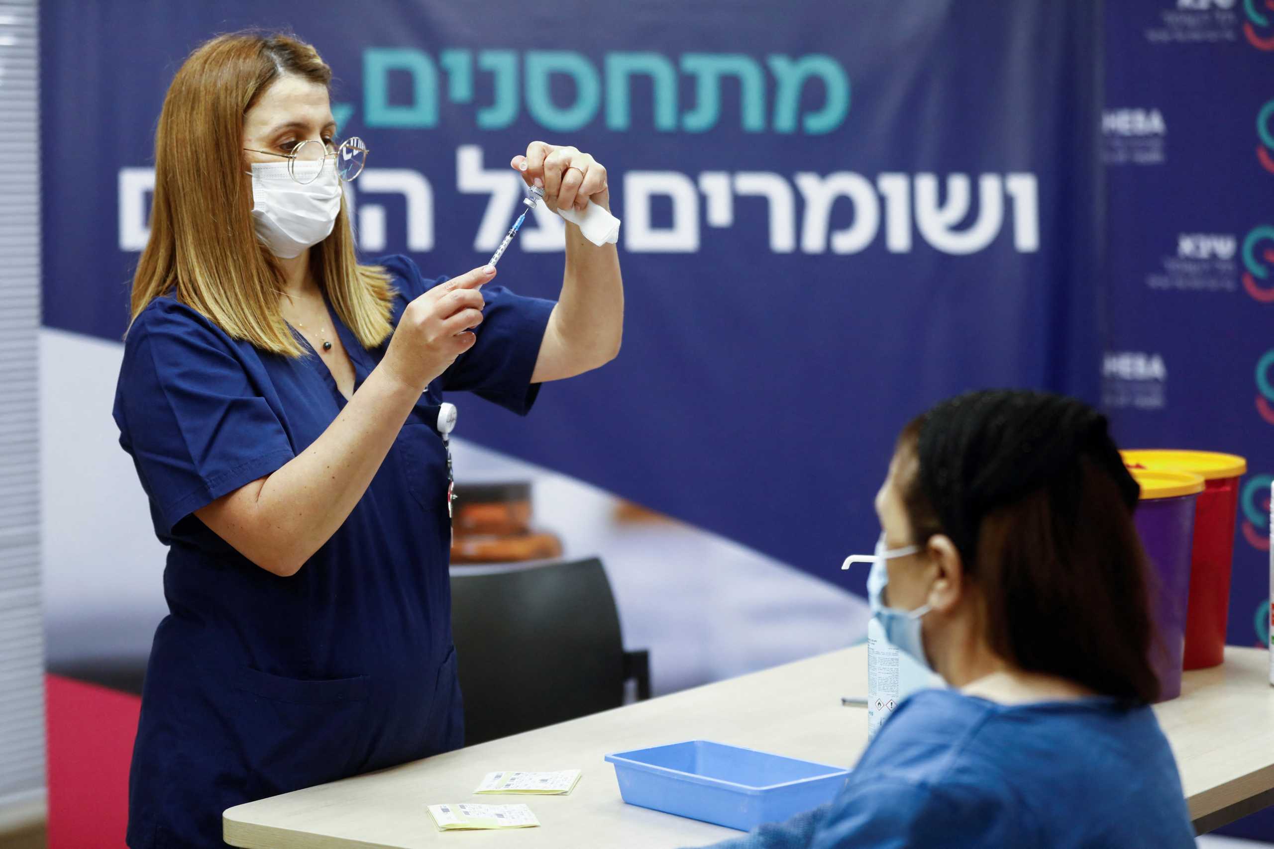 A medical worker prepares to give Malka Peer a fourth dose of the coronavirus disease (COVID-19) vaccine after Israel's Health Ministry approved a second booster for the immunocompromised, at Sheba Medical Center in Ramat Gan, Israel December 31, 2021. REUTERS