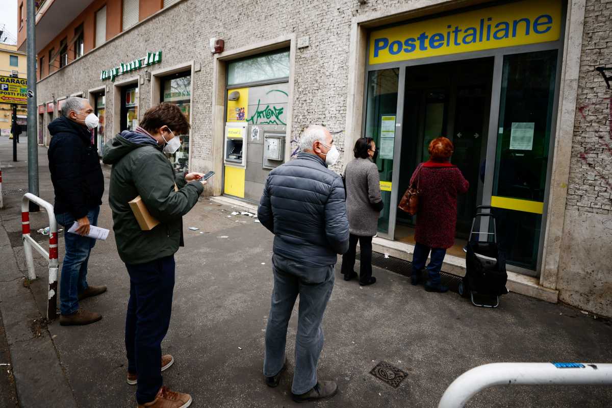 People wait in line outside a post office a day before COVID 'Green Pass' (health pass) becomes obligatory to access post offices, banks and many other stores and shops in Rome, Italy, January 31, 2022. REUTERS