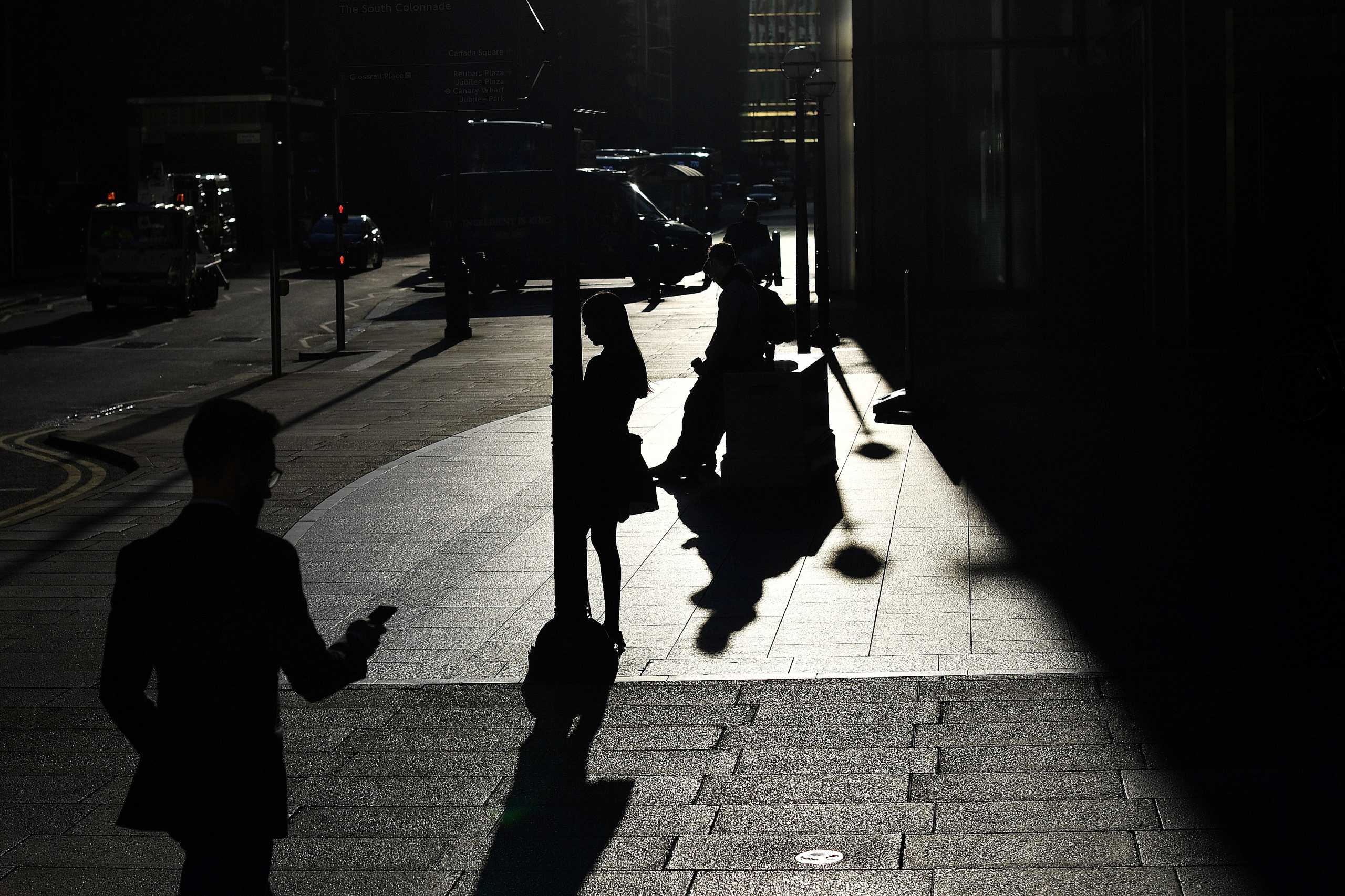 The early morning sun silhouettes commuters as they make their way through Canary Wharf in London, Britain September 5, 2019.  REUTERS