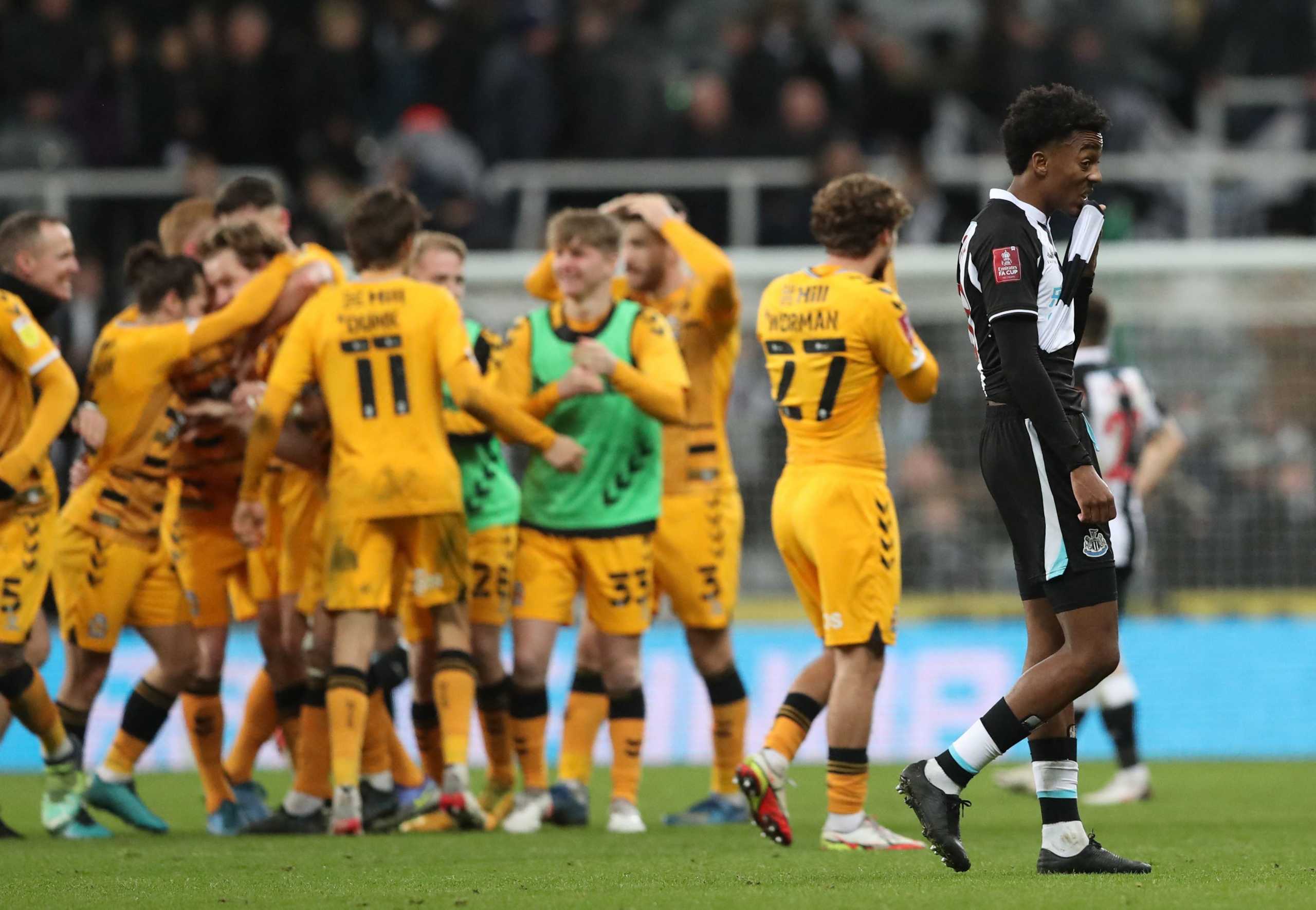 Soccer Football - FA Cup Third Round - Newcastle United v Cambridge United - St James' Park, Newcastle, Britain - January 8, 2022 Cambridge United players celebrate as Newcastle United's Joe Willock looks dejected after the match REUTERS
