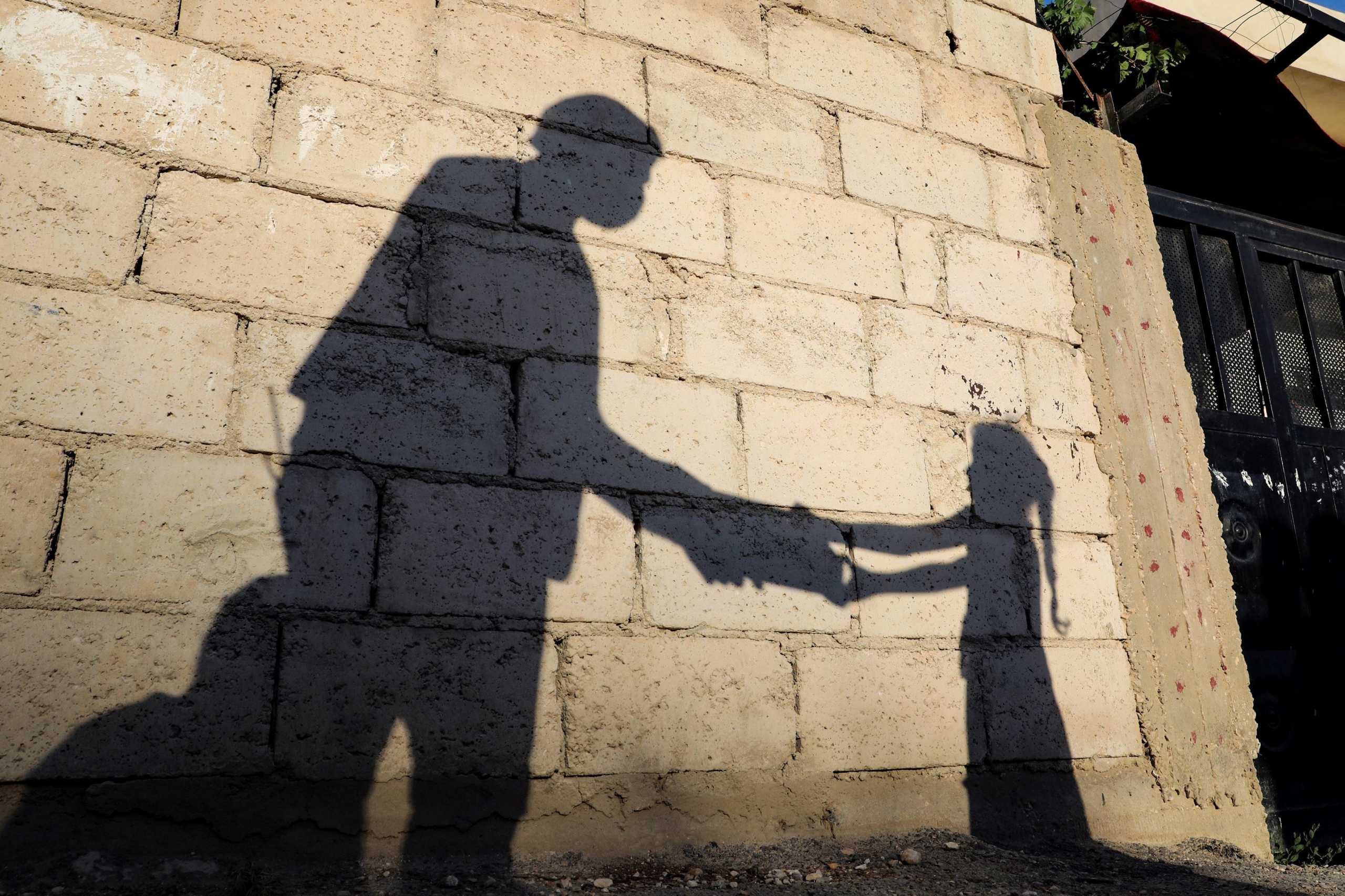The shadow of a girl receiving a meal for iftar, or the evening meal, to break fast from a member of "Tkiyet Um Ali" humanitarian services center is cast on a wall in front of her family home in the city of Russeifa, during the holy fasting month of Ramadan, amid concerns over the spread of coronavirus disease (COVID-19), in Jordan, April 28, 2020. Picture taken April 28, 2020. REUTERS