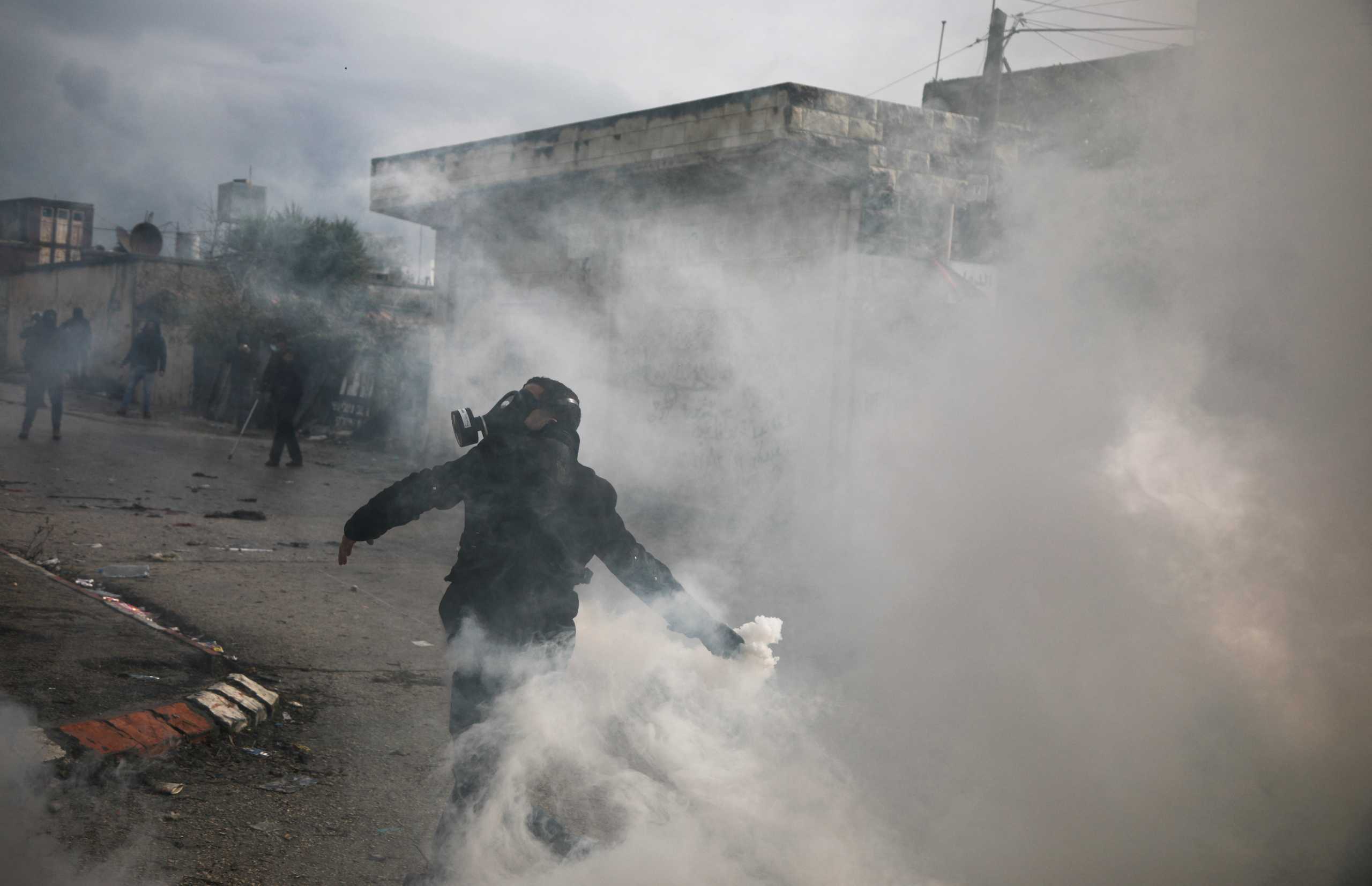 A Palestinian demonstrator is covered in smoke during a protest against Jewish settlements, in Burqa village, in the Israeli-occupied West Bank December 23, 2021. REUTERS