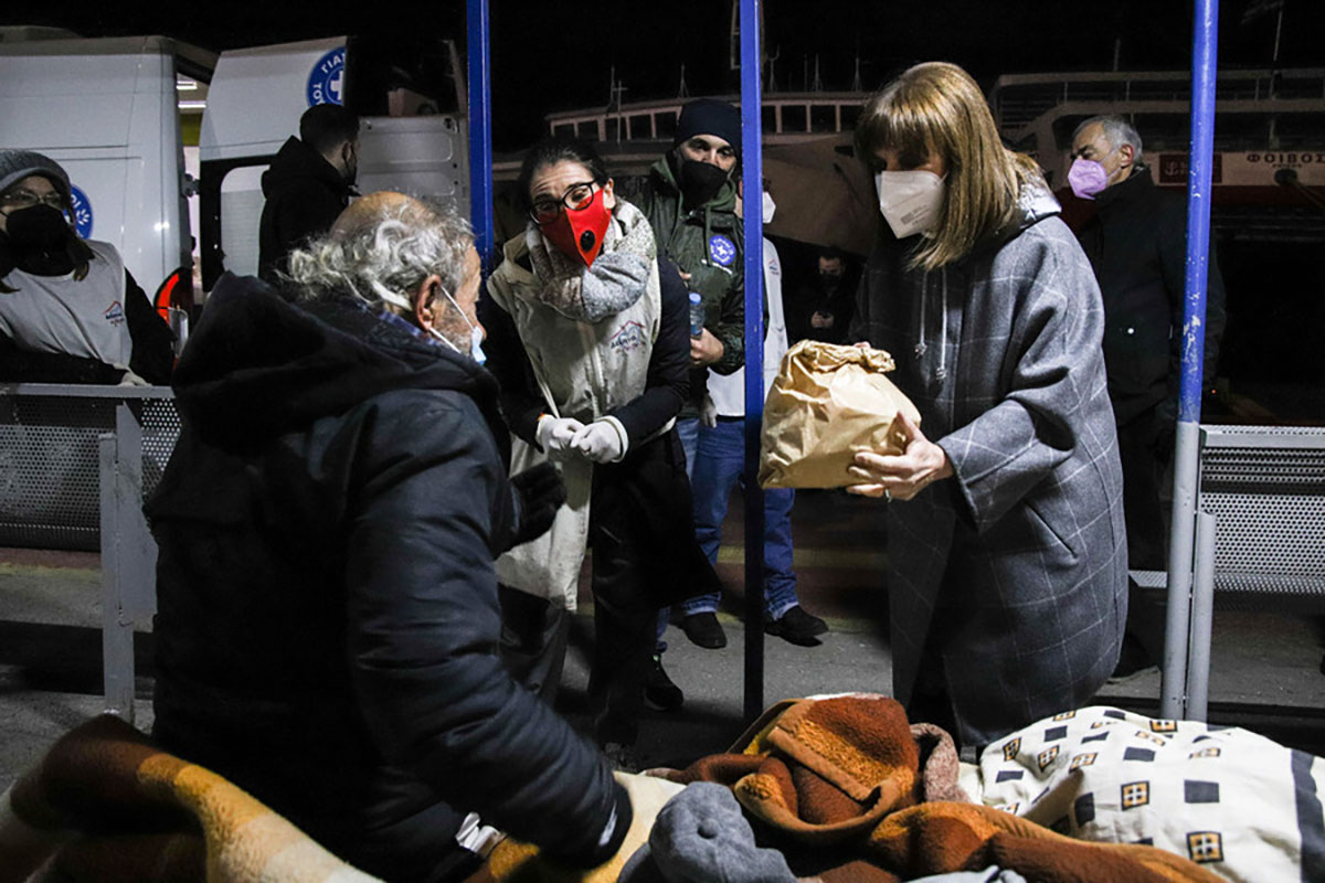Φωτογραφία που δόθηκε σήμερα στη δημοσιότητα και εικονίζει την  Πρόεδρο της Δημοκρατίας Κατερίνα Σακελλαροπούλου να μοιράζει φαγητό σε αστέγους, την Πέμπτη 13 Ιανουαρίου 2022, στο λιμάνι του Πειραιά. Κοντά σε αδύναμους και άστεγους συνανθρώπους μας, που δοκιμάζονται ιδιαίτερα αυτές τις ημέρες λόγω της βαρυχειμωνιάς, βρέθηκε χθες το βράδυ η Πρόεδρος της Δημοκρατίας, Κατερίνα Σακελλαροπούλου, συνοδευόμενη από τον γγ Κοινωνικής Αλληλεγγύης και Καταπολέμησης της Φτώχειας, Γιώργο Σταμάτη. Μαζί με εθελοντές από τους Γιατρούς του Κόσμου και το «Δείπνο Αγάπης», η κ. Σακελλαροπούλου συμμετείχε στη διανομή φαγητού σε άστεγους στην Πύλη Ε7-Ε9 του Λιμένος Πειραιώς. Δεν είναι η πρώτη φορά που η Πρόεδρος της Δημοκρατίας βρίσκεται κοντά σε συμπολίτες μας που χρειάζονται βοήθεια, καθώς και την παραμονή των Χριστουγέννων είχε συμμετάσχει στην ίδια δράση στο λιμάνι του Πειραιά και είχε δώσει την υπόσχεση ότι θα επιστρέψει, όπως έκανε χθες, σε μία από τις πιο κρύες νύχτες του χειμώνα. Πολλοί από τους άστεγους την αναγνώρισαν και έσπευσαν να συνομιλήσουν μαζί της, λέγοντας ότι ξαφνιάστηκαν ευχάρισ