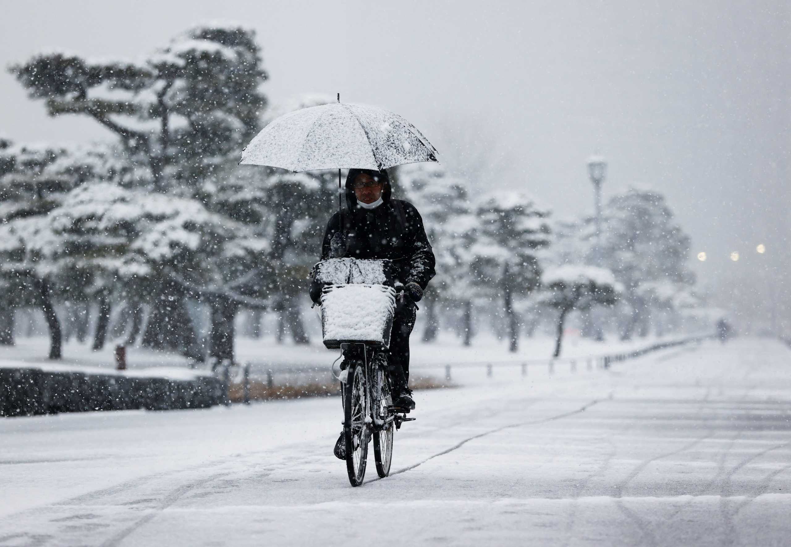 A man rides a bicycle in the snowfall, amid the coronavirus disease (COVID-19) pandemic, in Tokyo, Japan January 6, 2022. REUTERS