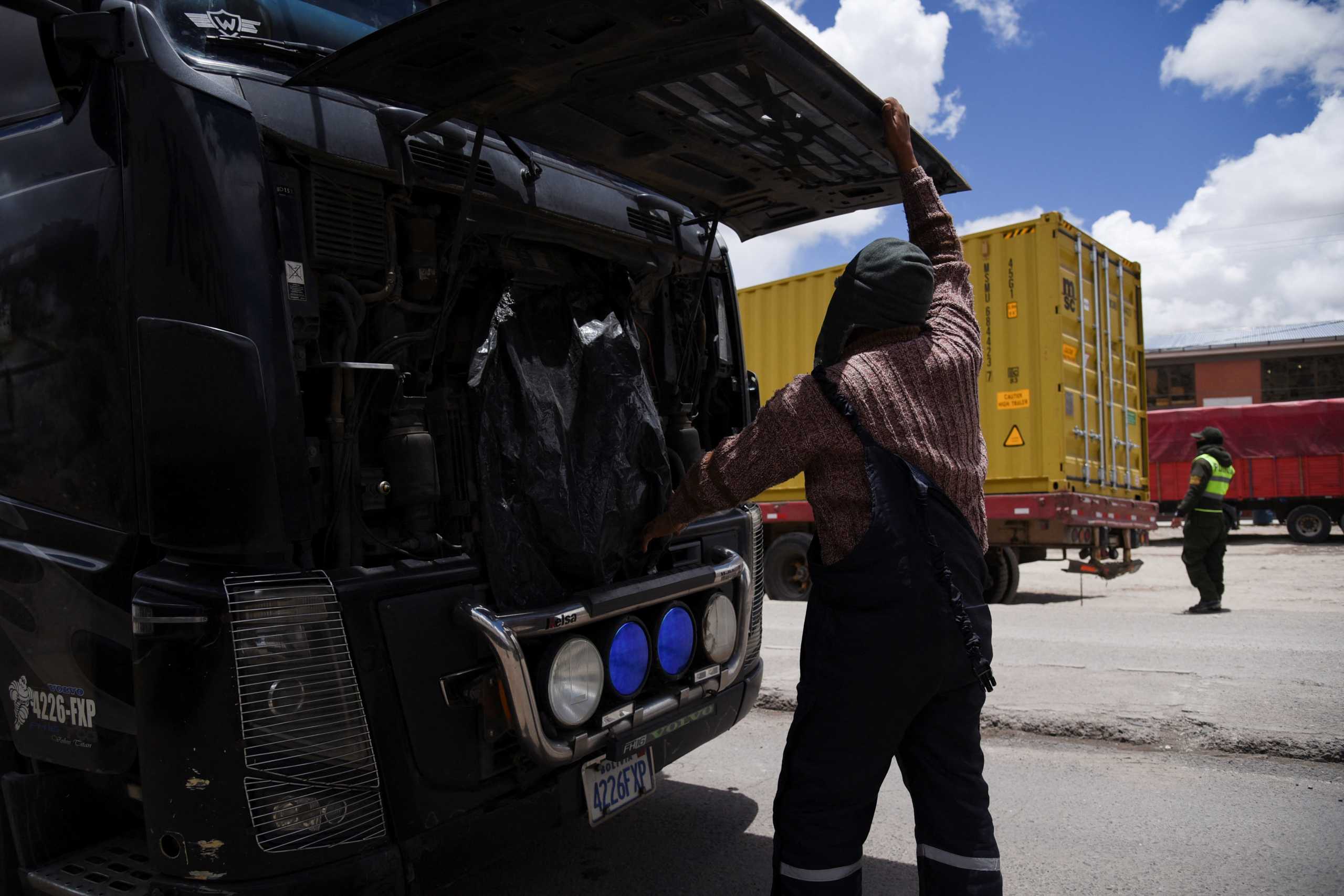 Trucker Ludvi Inturias Alcocer, who has been stranded for five days, inspects his truck engine near the Bolivian border amid a backlog of coronavirus disease (COVID-19) testing that would allow truckers to enter Chile, in Tambo Quemado, Bolivia January 13, 2022. REUTERS