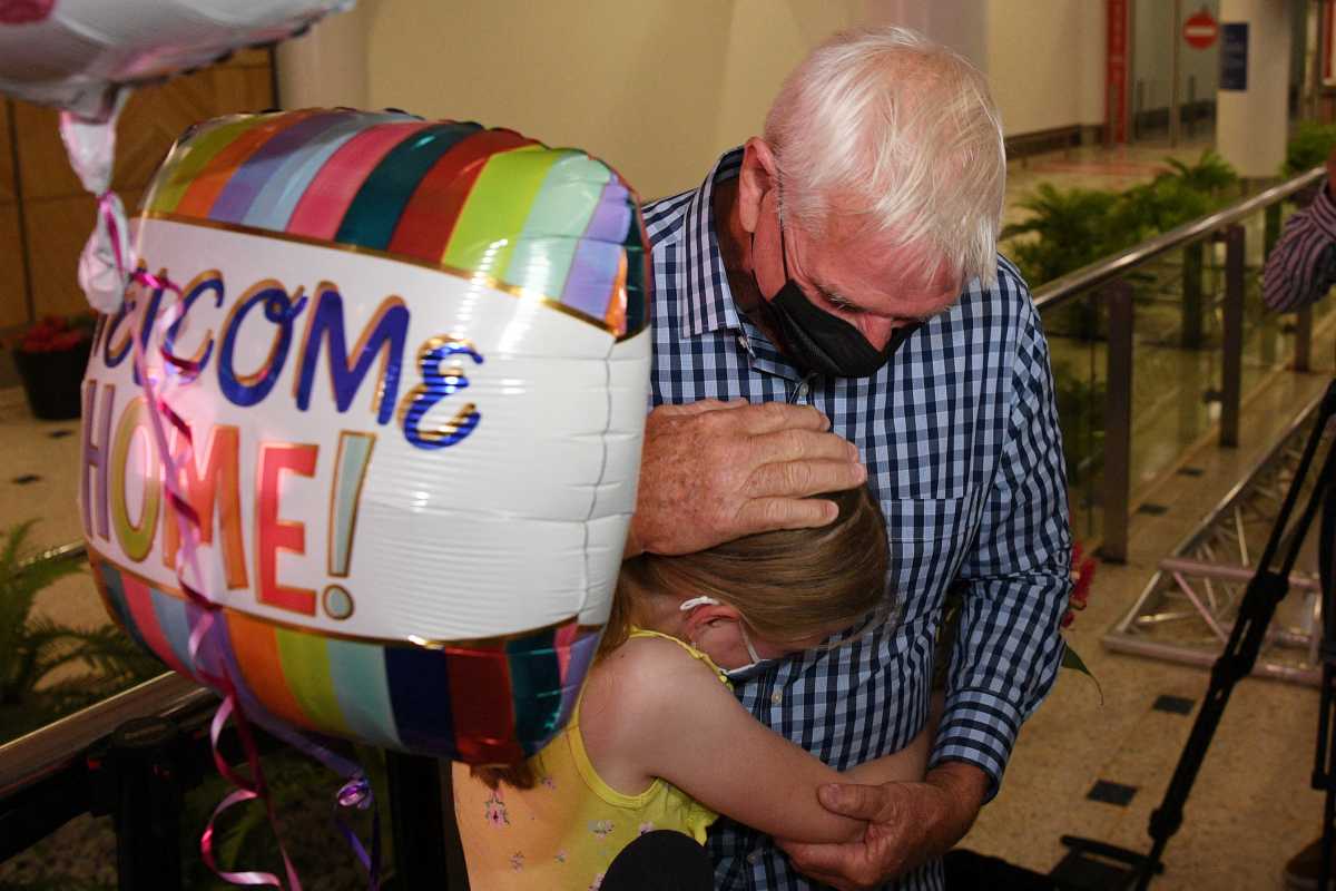 Charlotte Roempke, 8, welcomes her grandfather Bernie Edmonds as he arrives at Sydney International Airport after Australia reopened its international borders to travelers vaccinated against the coronavirus disease (COVID-19), in Sydney, Australia February 21, 2022. AAP Image