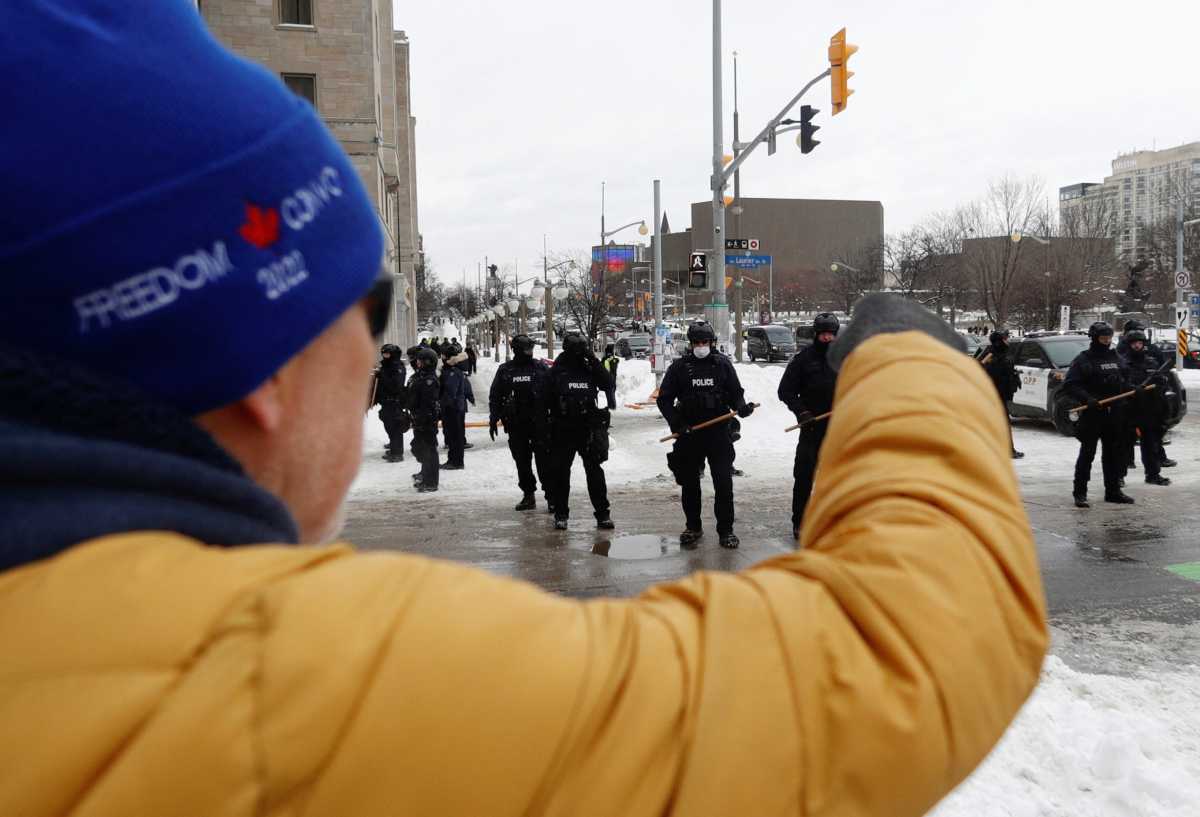 A person supporting the "Freedom Convoy" protesters shouts at Canadian police officers standing guard, as police work to evict the last of the trucks and supporters occupying the downtown core, three weeks after a protest against coronavirus disease (COVID-19) vaccine mandates began, in Ottawa, Ontario, Canada, February 20, 2022. REUTERS