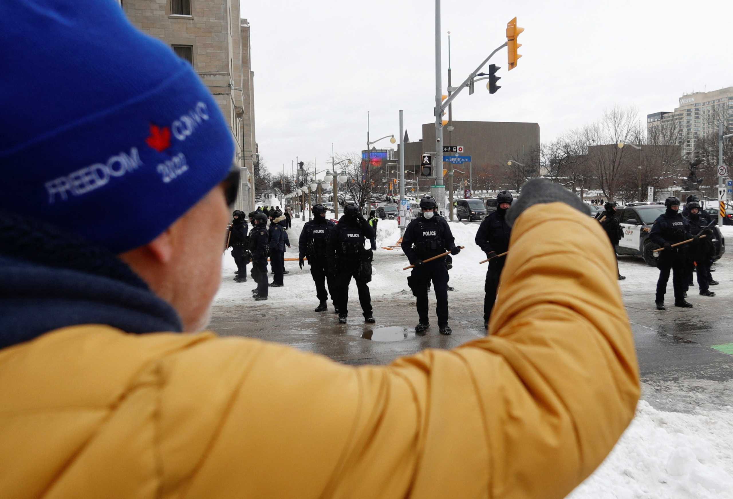 A person supporting the "Freedom Convoy" protesters shouts at Canadian police officers standing guard, as police work to evict the last of the trucks and supporters occupying the downtown core, three weeks after a protest against coronavirus disease (COVID-19) vaccine mandates began, in Ottawa, Ontario, Canada, February 20, 2022. REUTERS