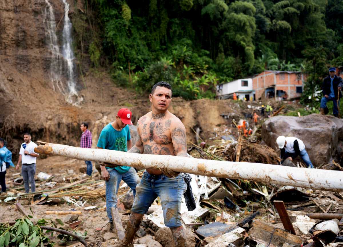 People remove debris following a landslide caused by heavy rains, that killed and injured residents and destroyed homes, in Pereira, Colombia, February 8, 2022. REUTERS