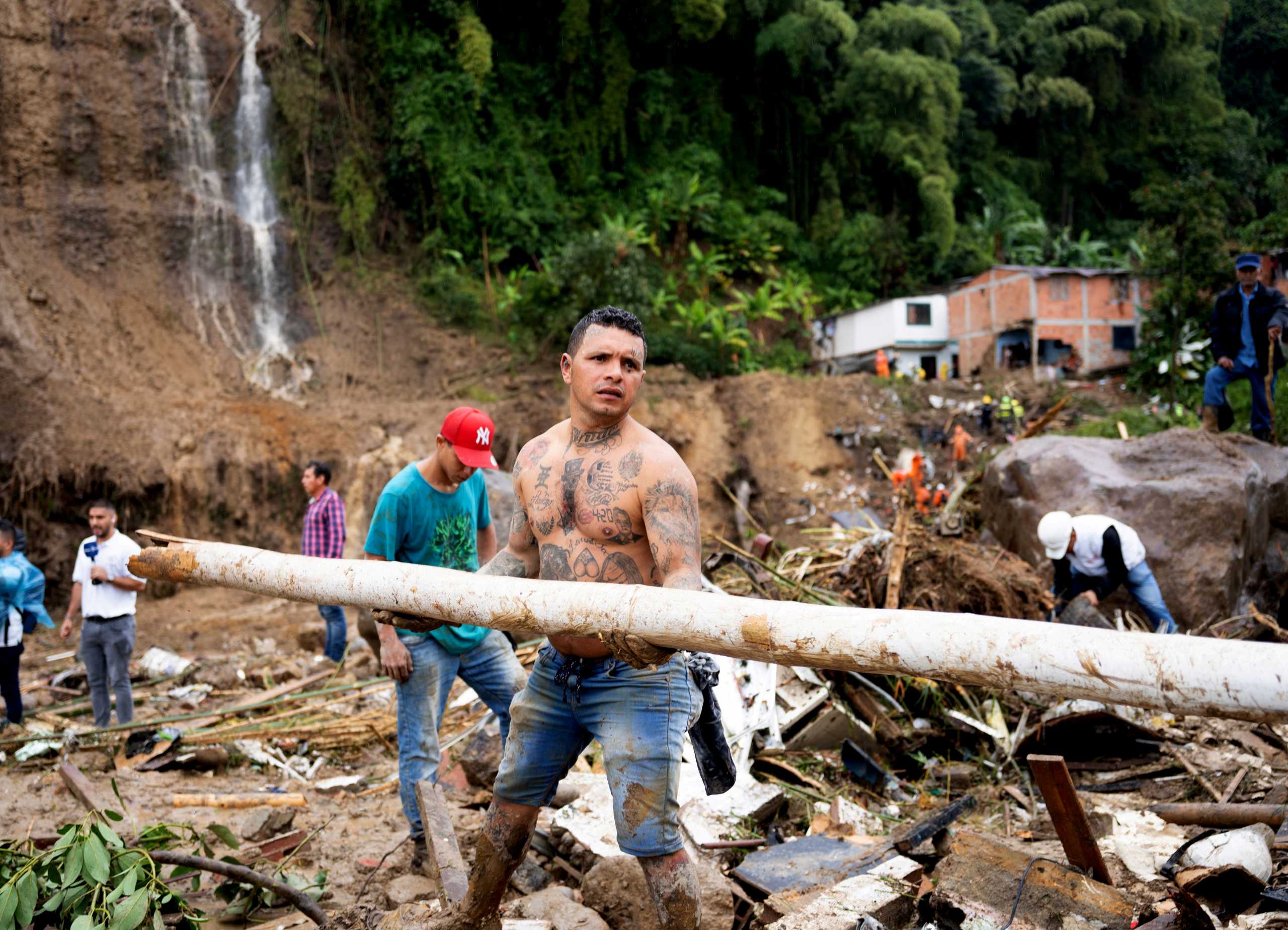 People remove debris following a landslide caused by heavy rains, that killed and injured residents and destroyed homes, in Pereira, Colombia, February 8, 2022. REUTERS