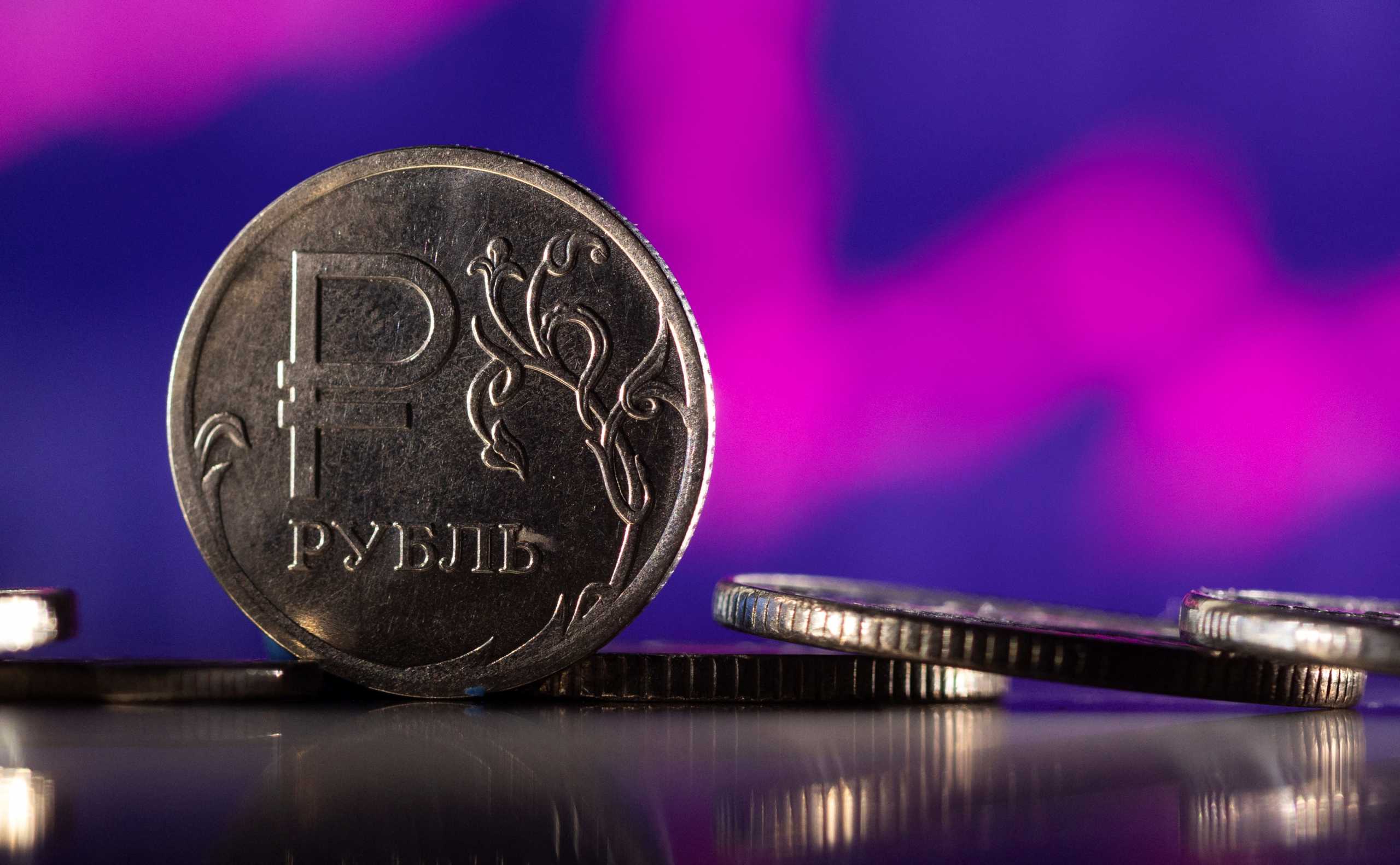 Russian Rouble coins are seen in front of displayed descending stock graph in this illustration taken, February 24, 2022. REUTERS