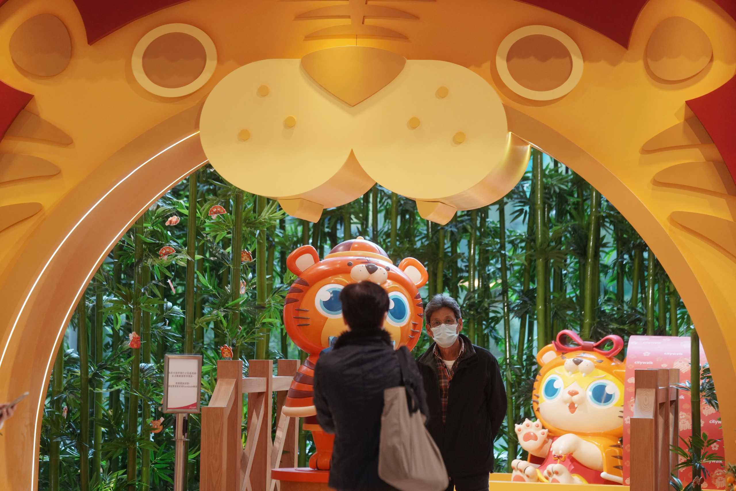 A man wearing a face mask poses for pictures in front of a tiger installation for the Lunar New Year, following the coronavirus disease (COVID-19) outbreak in Hong Kong, China February 8, 2022. REUTERS
