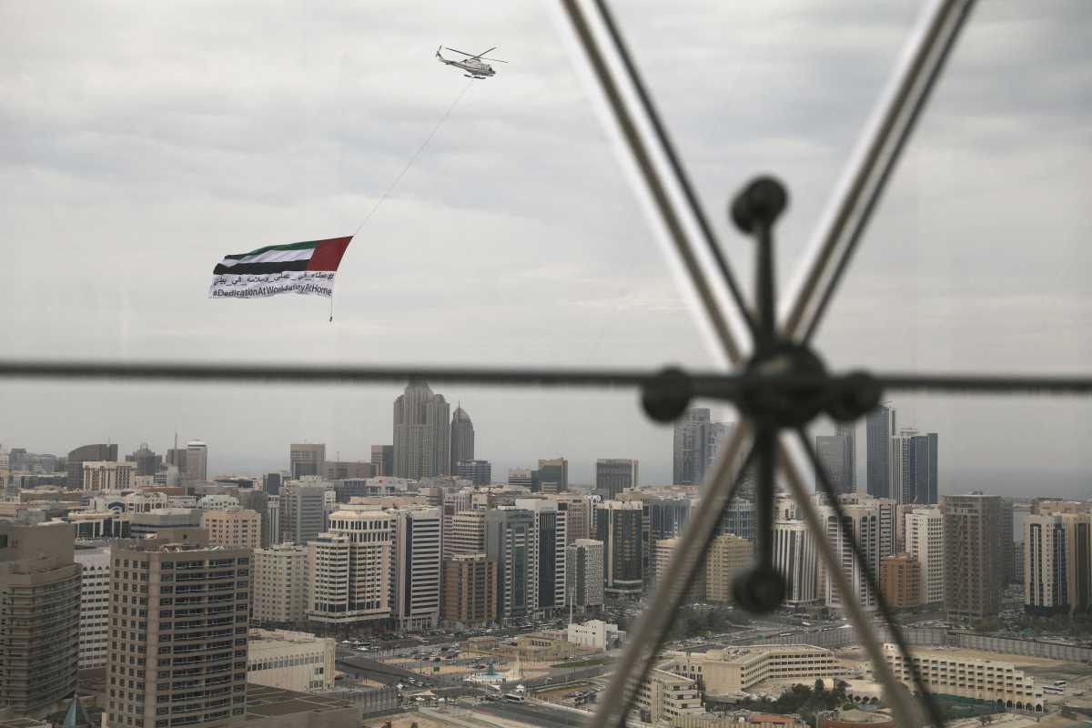 FILE PHOTO: A helicopter flies over the downtown skyline of Abu Dhabi, United Arab Emirates, April 20, 2020. REUTERS