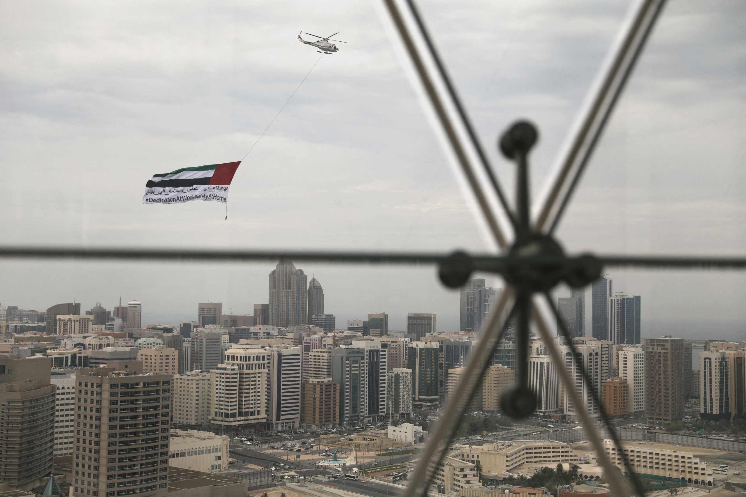 FILE PHOTO: A helicopter flies over the downtown skyline of Abu Dhabi, United Arab Emirates, April 20, 2020. REUTERS