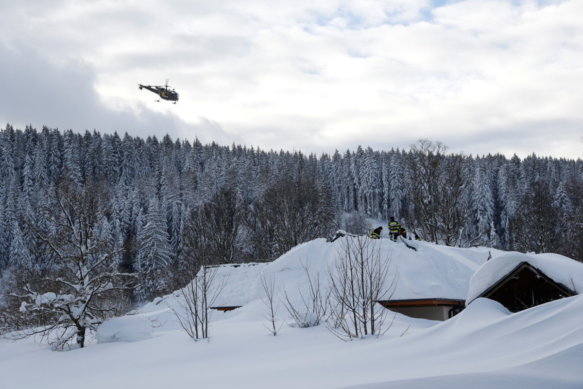 A helicopter flies over snow covered rooftops in the village of Ramsau, Austria January 15, 2019.  REUTERS