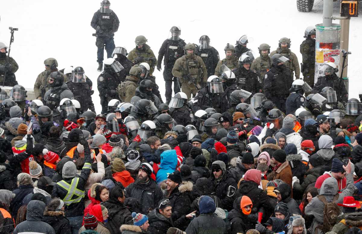 Canadian police officers stand guard and watch protestors, as they work to restore normality to the capital while trucks and demonstrators continue to occupy the downtown core for more than three weeks to protest against pandemic restrictions in Ottawa, Ontario, Canada, February 19, 2022.  REUTERS