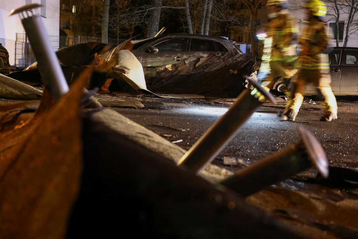 Firefighters walk past debris from a roof following heavy storms in Berlin, Germany, February 19, 2022. REUTERS