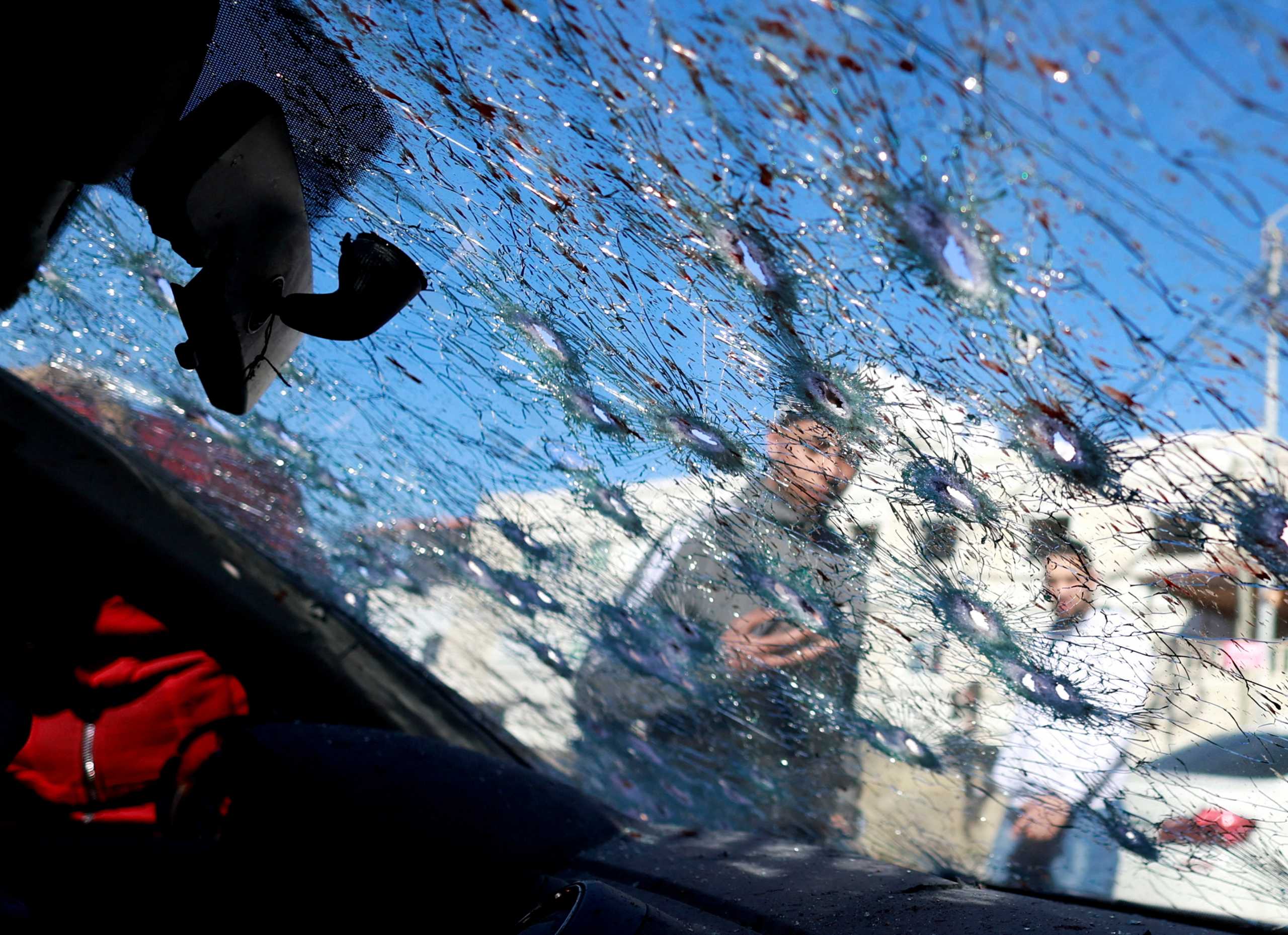 People look at a cracked windscreen with bullet holes at the scene where three Palestinian gunmen were killed by Israeli forces, in Nablus in the Israeli-occupied West Bank February 8, 2022. REUTERS