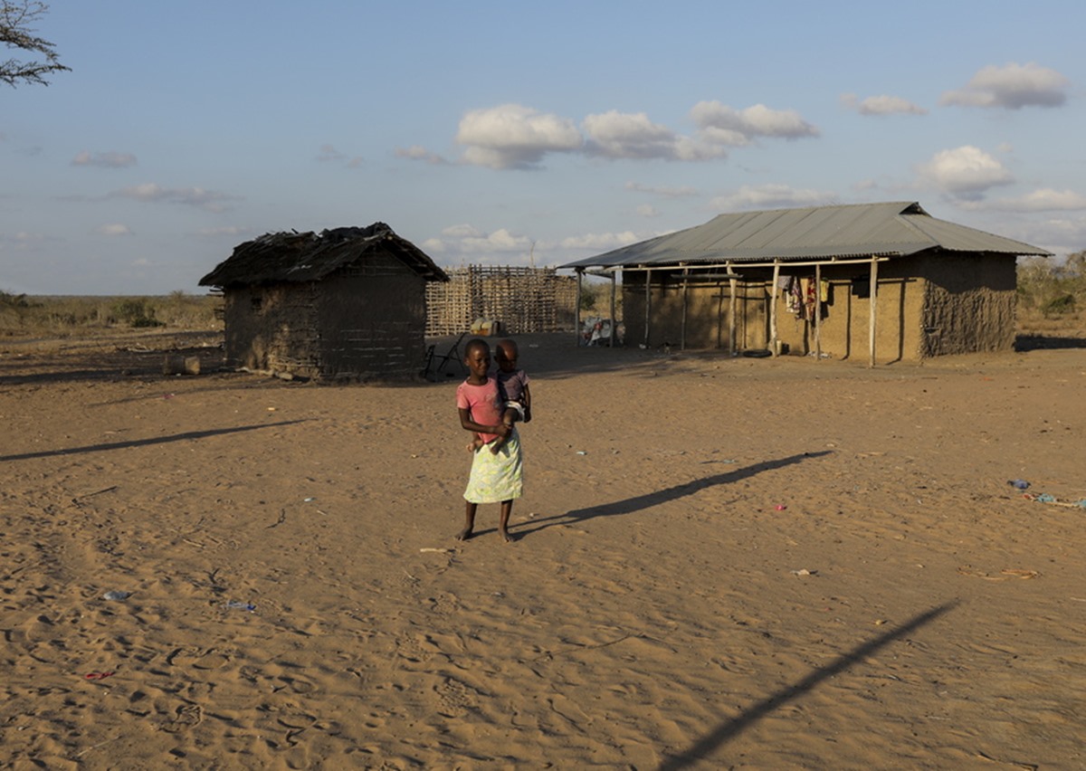 epa09524734 A young girl carrues her sibling looks on outside their house as she plays with other kids after they were left behind to look after their village as other villagers went to receive food relief from the government in the drought-stricken region of Milore village, in Ganze, in Kilifi County, 07 October 2021 (issued 15 October 2021). An estimated over 2 million Kenyans face starvation due to the ongoing drought that has affected majorly ten counties suffering from lack of water and harvest living thousands of animals died in the North, North East and Coast, some of the most affected regions are in the coastal region including Kilifi, Lamu and Tana River. Kenya President Uhuru Kenyatta declared the drought as a “National Disaster” last month and ordered the immediate release of emergency relief food for the victims which the government started to distribute last week. Residents of the Ganze region in Kilifi which is one of the most affected regions by the drought, are forced to walk for more than six hours to fetch water from one of the 20% water pans remaining with water as 80% of the rest have dried up and they have also resulted to slaughtering and drying the meat from their animals that die due to hunger as a way of preserving some food for later use as they wait on the relief food. More than 400,000 people suffer from water shortage in the coastal region and more than 6,500 heard of cattle have died in Kilifi County and more than 4,000 in Tana River, according to Hassan Musa Director of Kenya Red Cross, Coast Region.  EPA