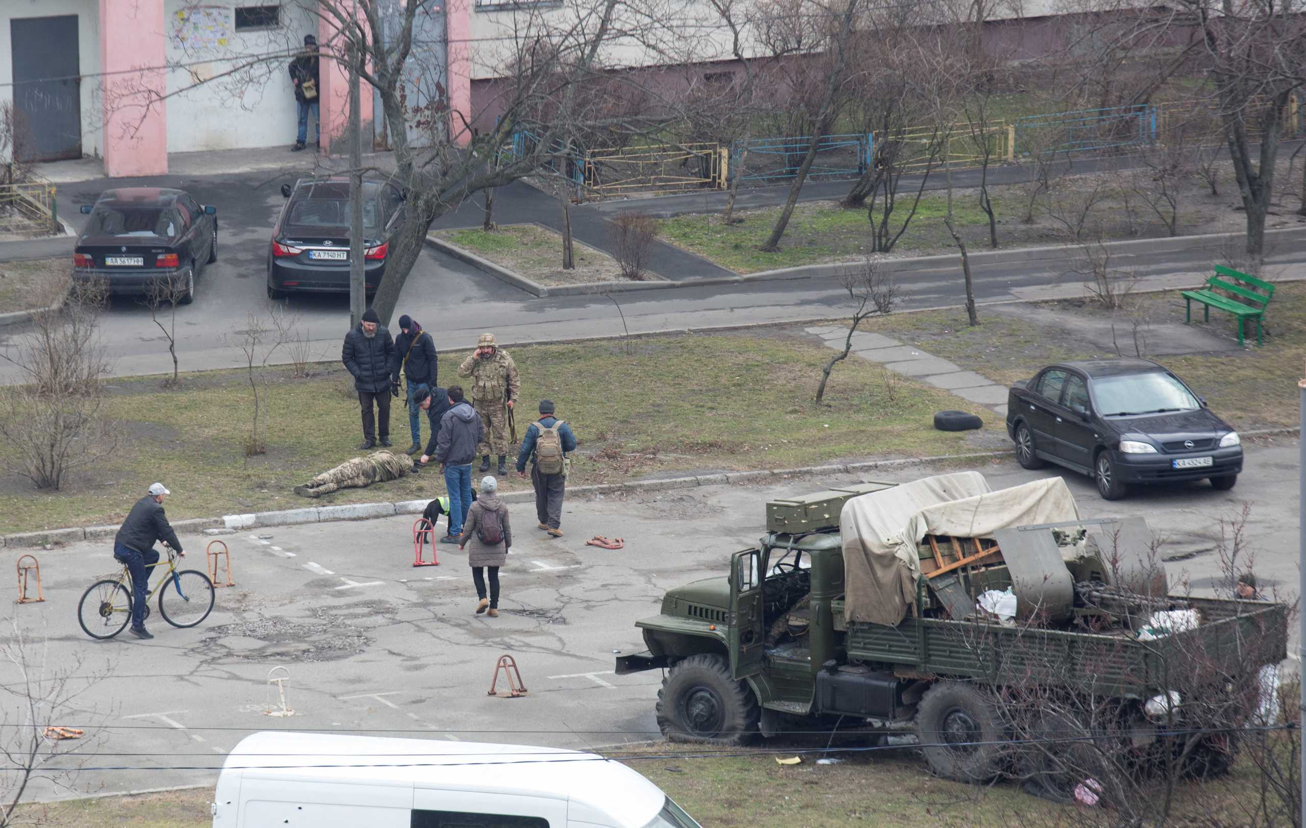 SENSITIVE MATERIAL. THIS IMAGE MAY OFFEND OR DISTURB  People surround a person wearing a military uniform, who lies on the ground near a damaged unidentified military truck at a residential area in Kyiv, Ukraine February 25, 2022. REUTERS