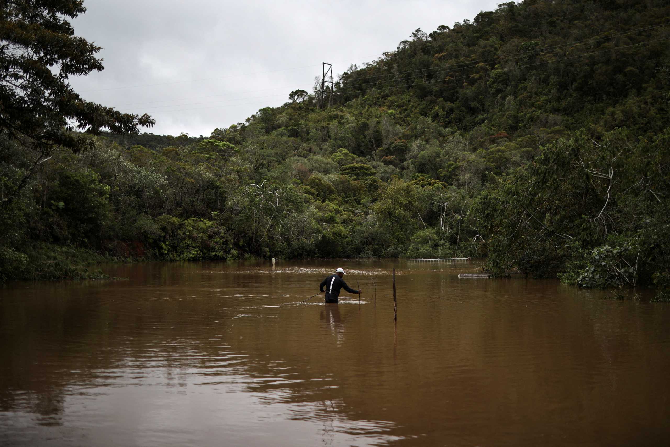 A man puts wooden sticks as marks at a flooded area, as Cyclone Batsirai sweeps inland, in Vohiparara, Madagascar, February 6, 2022. REUTERS
